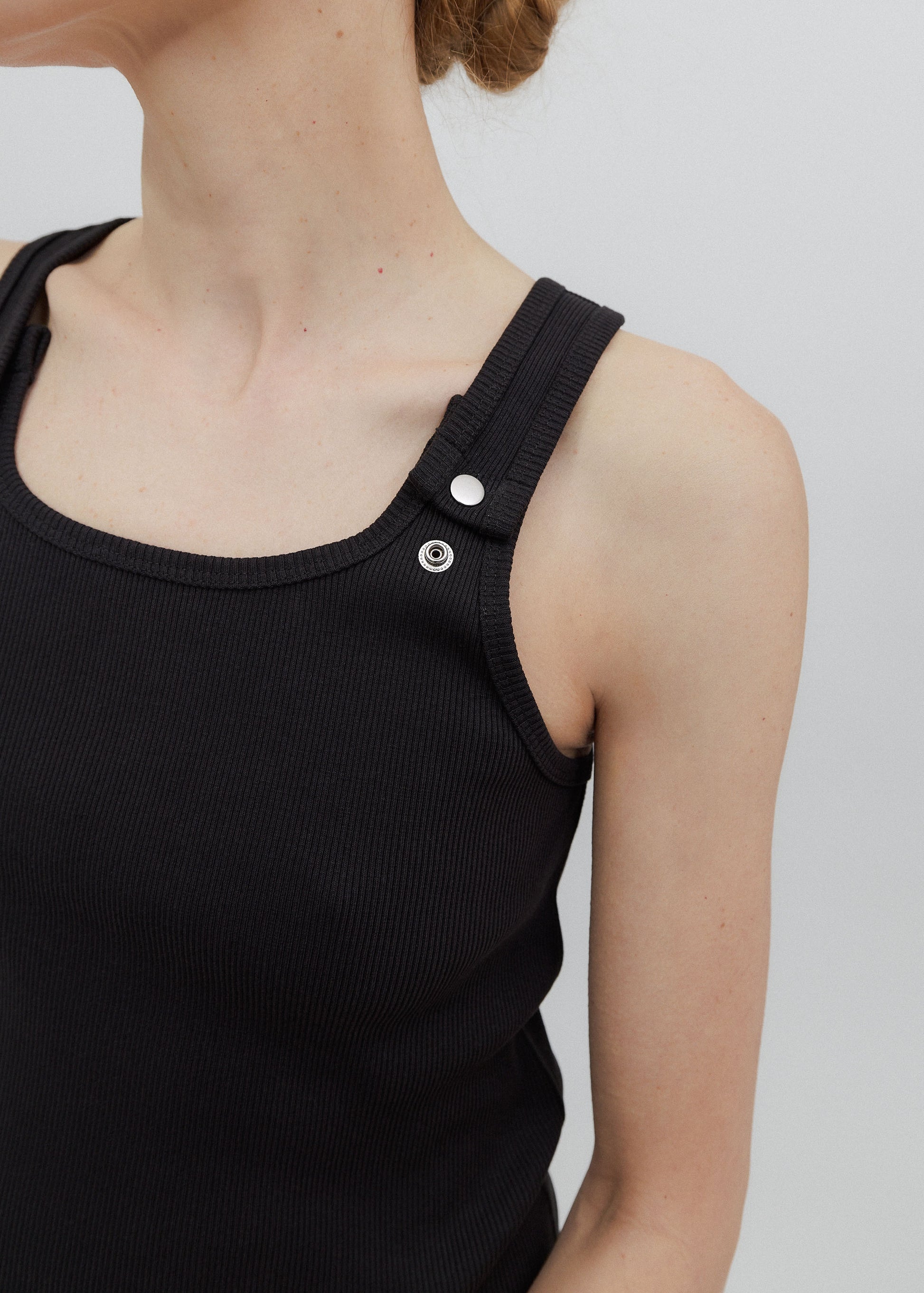 Black tank top with button details on a plain background