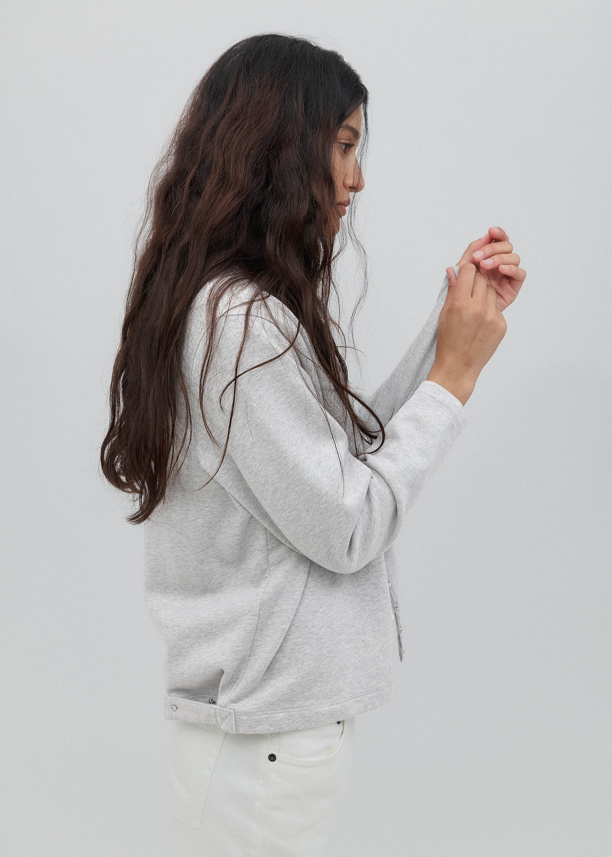 Woman wearing a light gray hoodie against a plain background