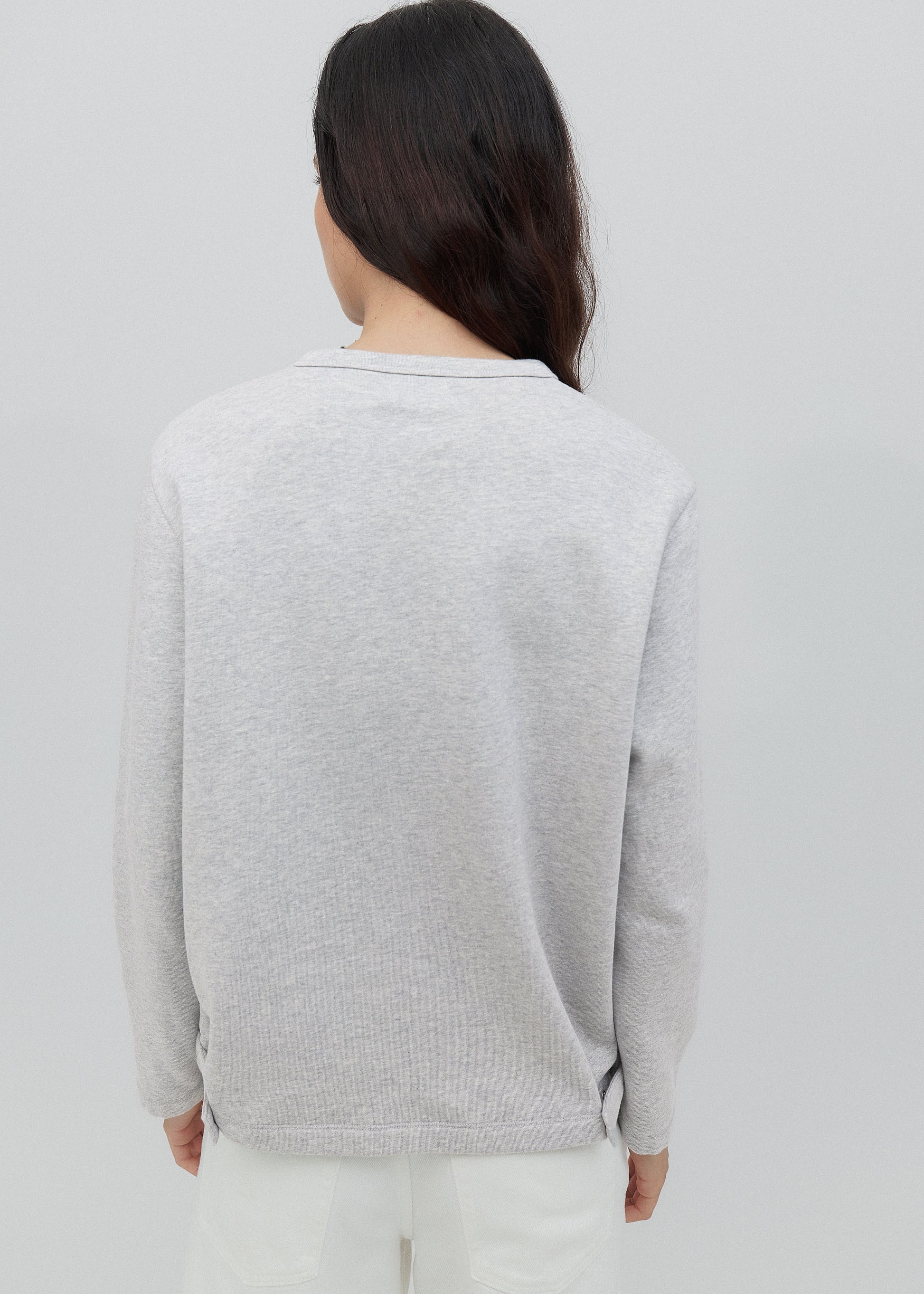 Person wearing a light gray sweater on a plain background