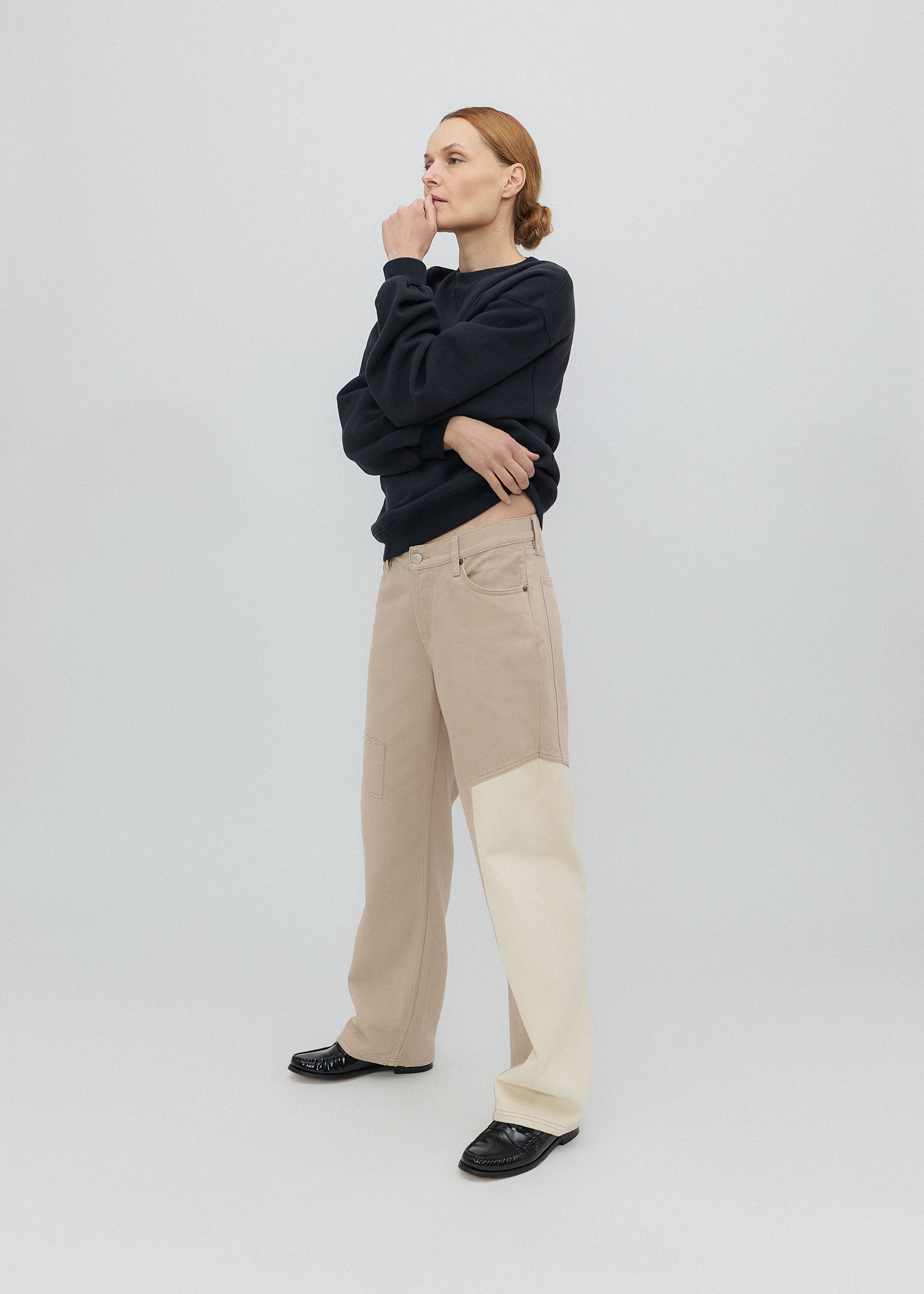 Woman wearing a black sweater and beige pants on a white background