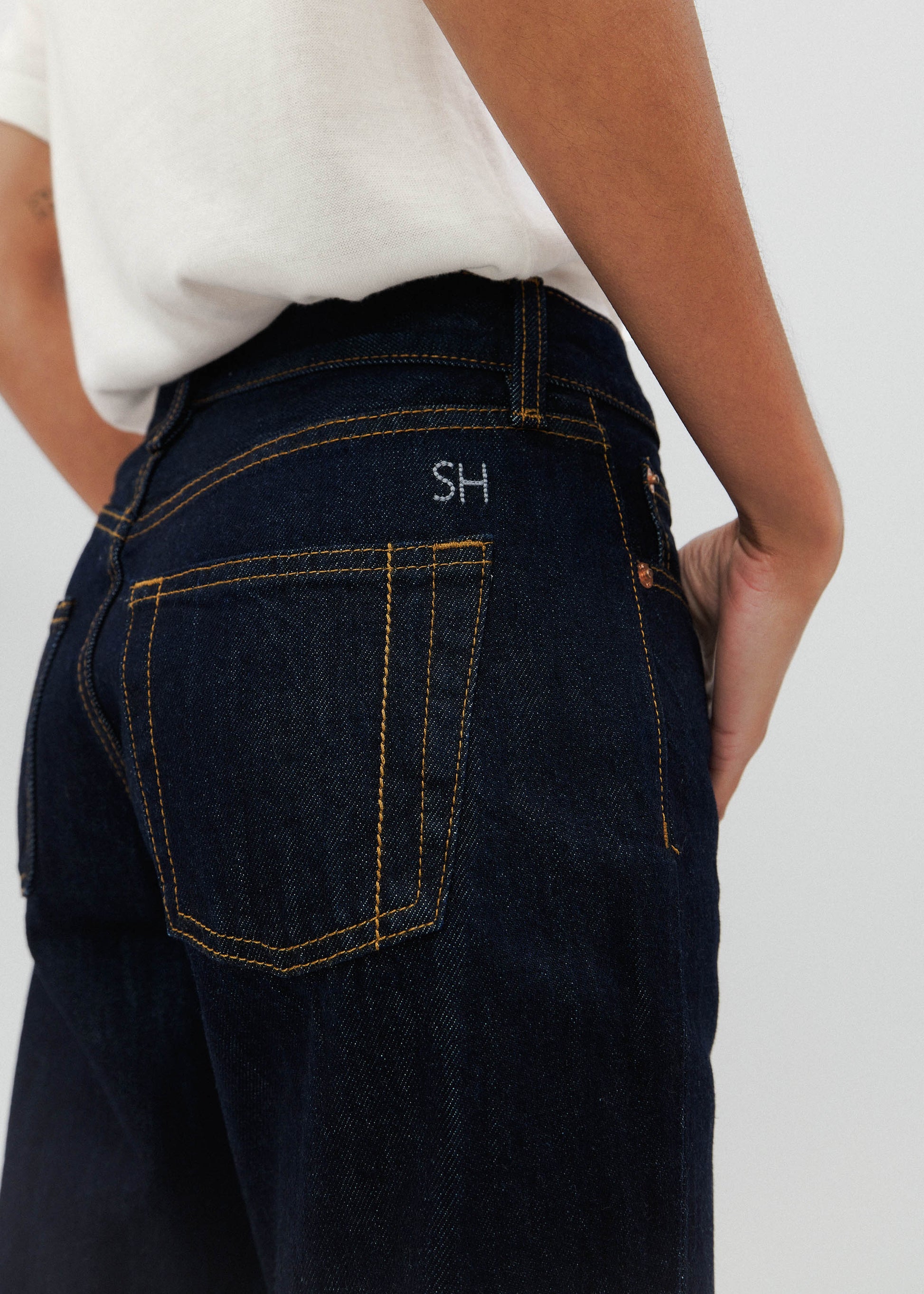 Dark blue jeans with a visible brand logo on the pocket against a white background