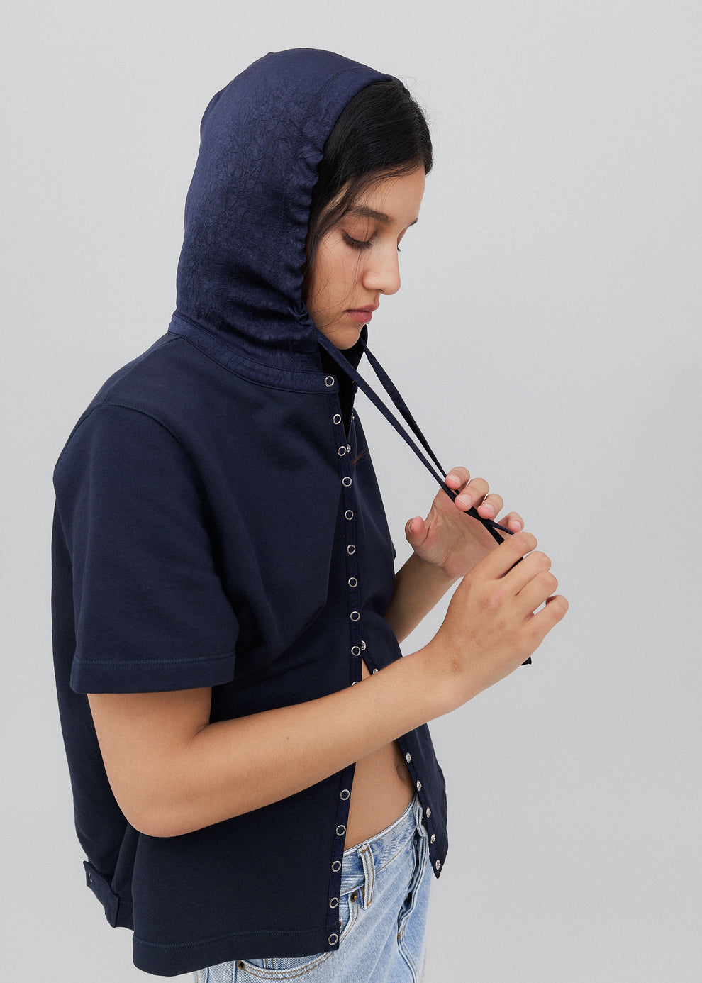 Person wearing a navy blue hoodie with button details on a plain background