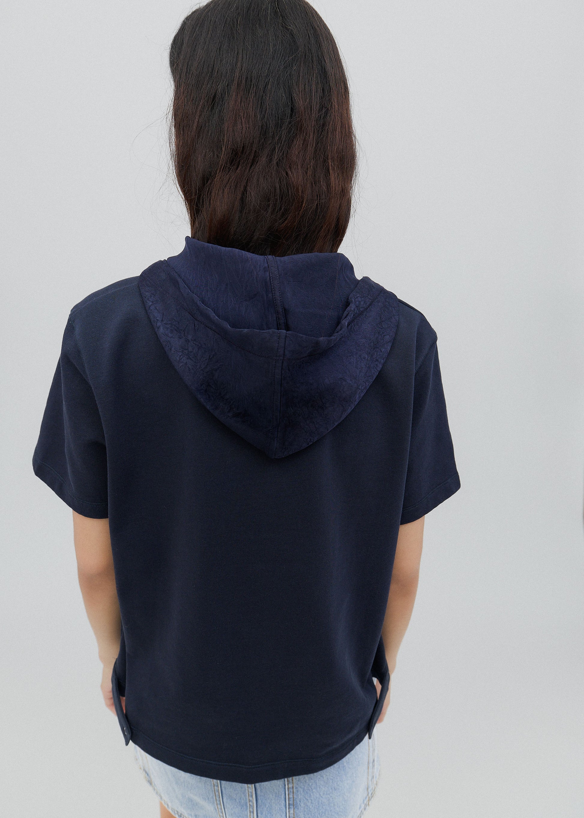 Person wearing a navy blue hoodie with a plain background