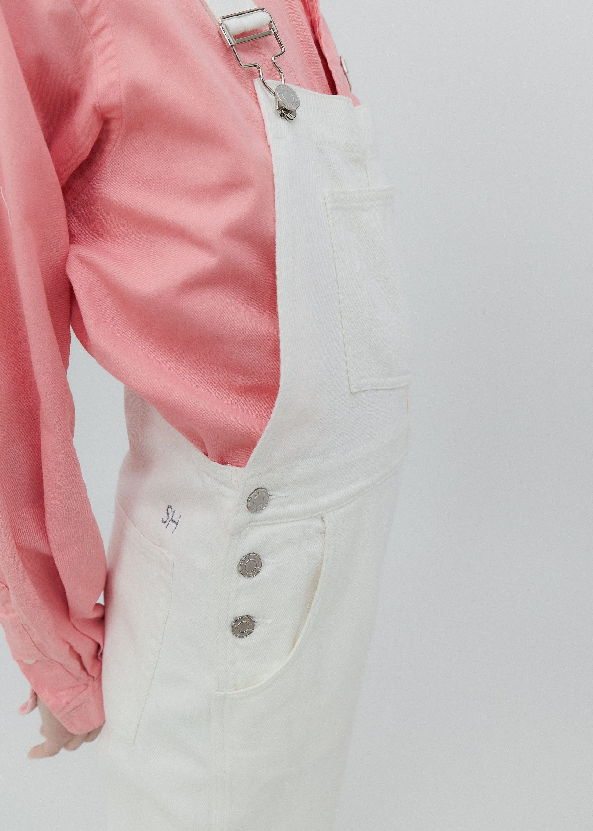 White denim overalls with a pink jacket on a light gray background