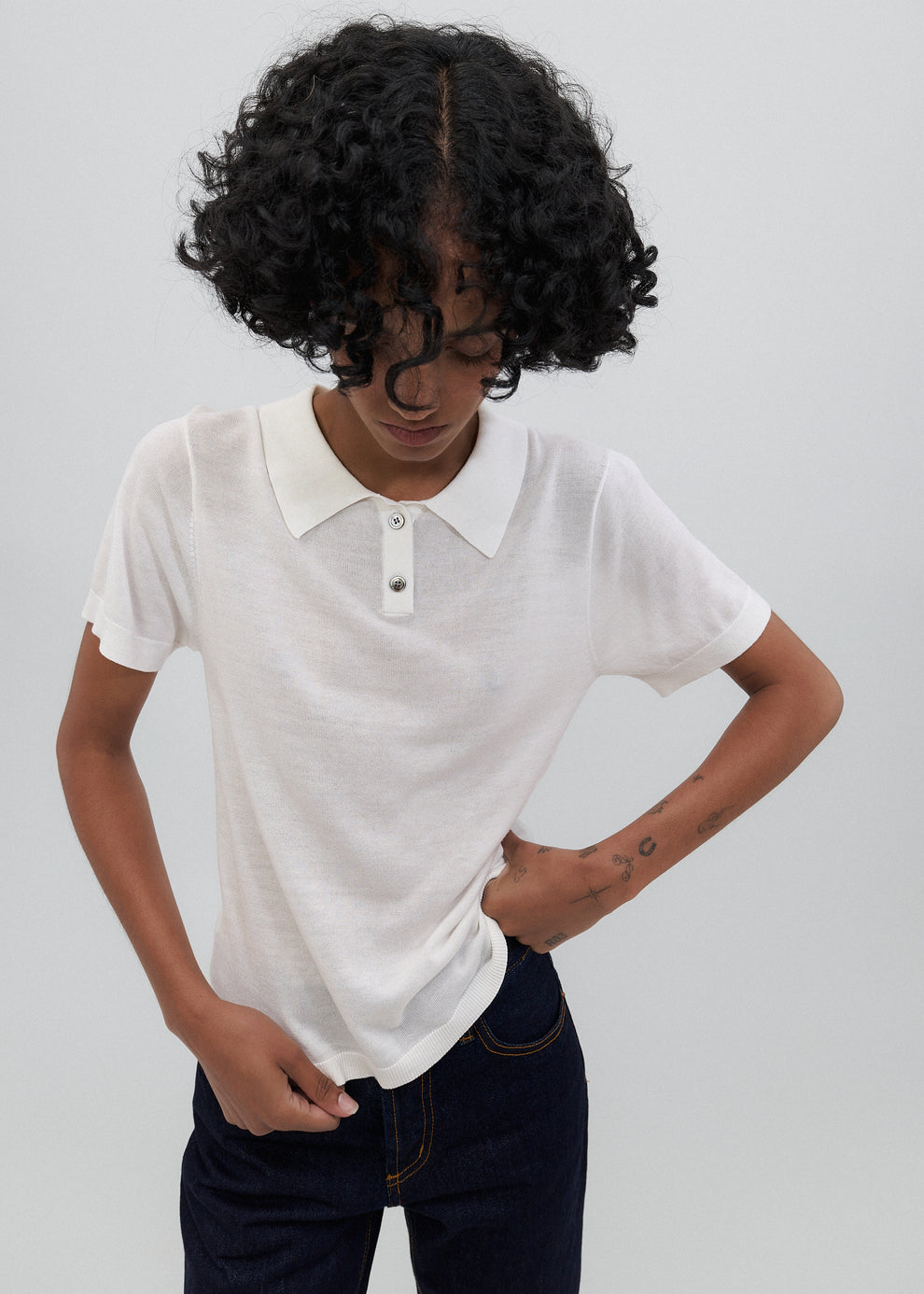 Person wearing a white polo shirt with a plain background