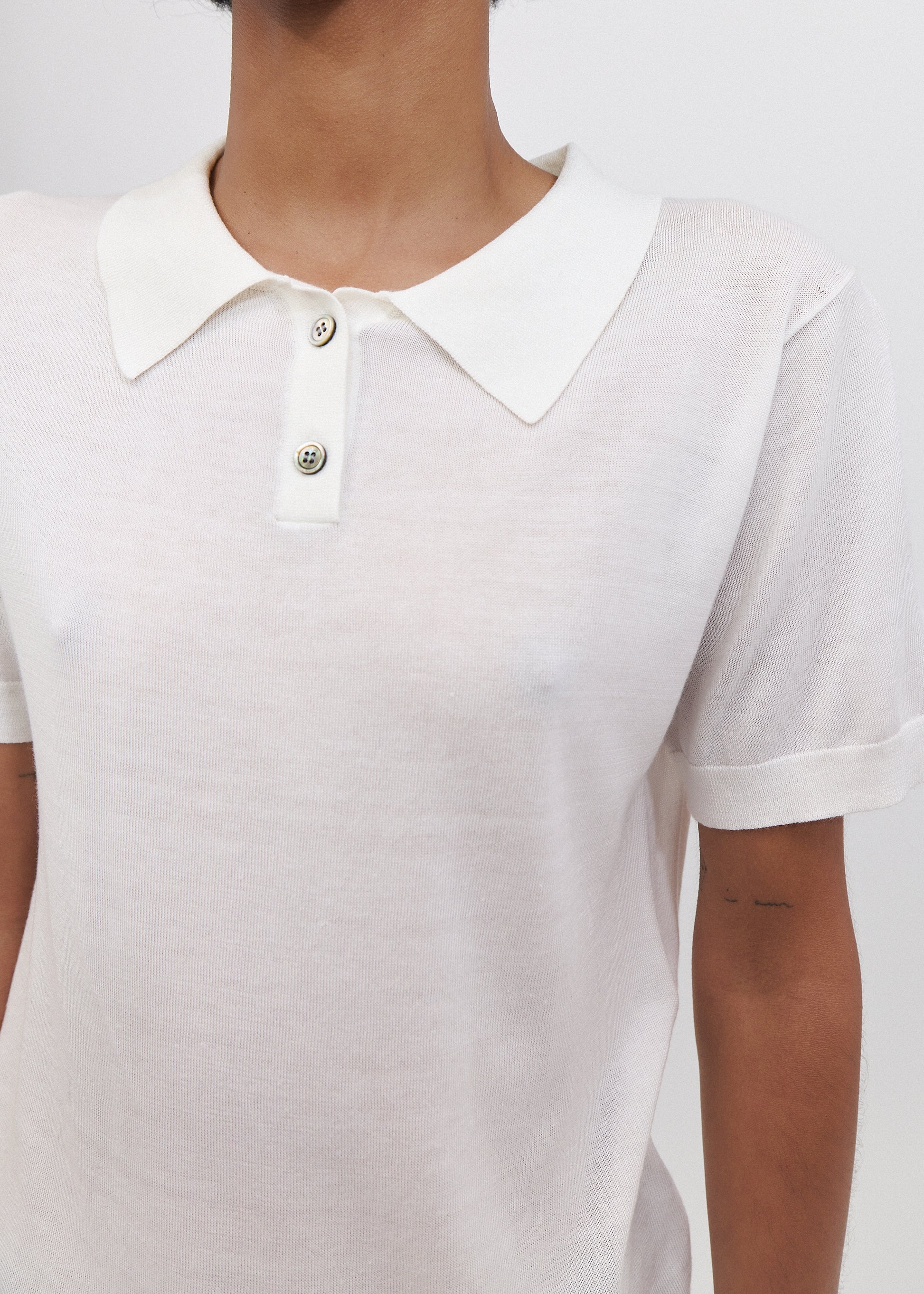 White polo shirt worn by a person on a plain background