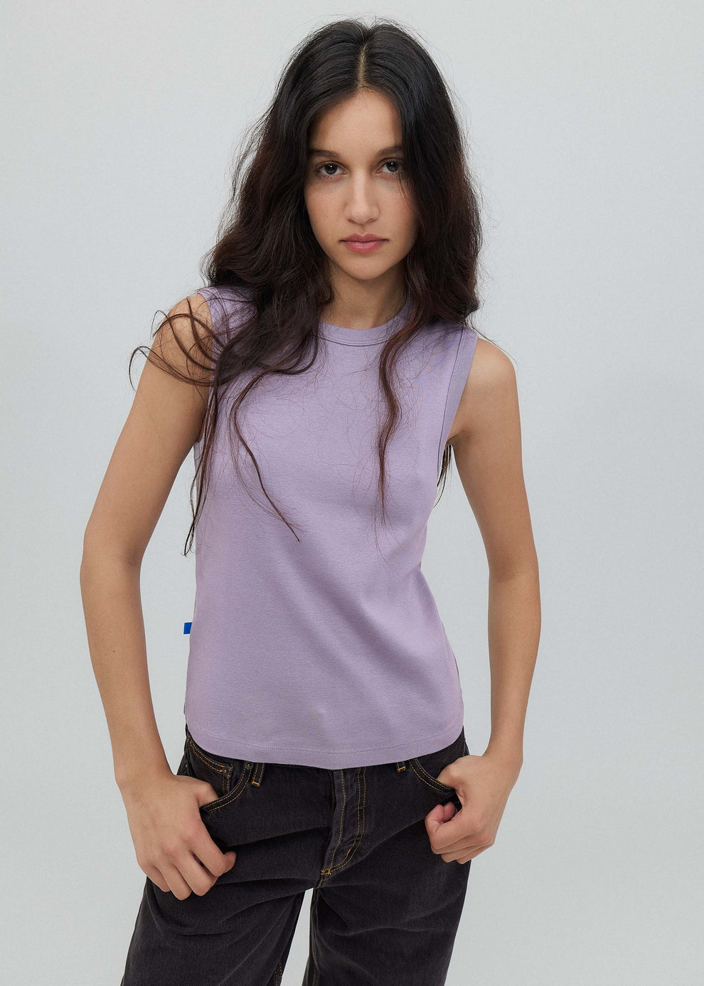 Woman wearing a light purple sleeveless top against a plain background