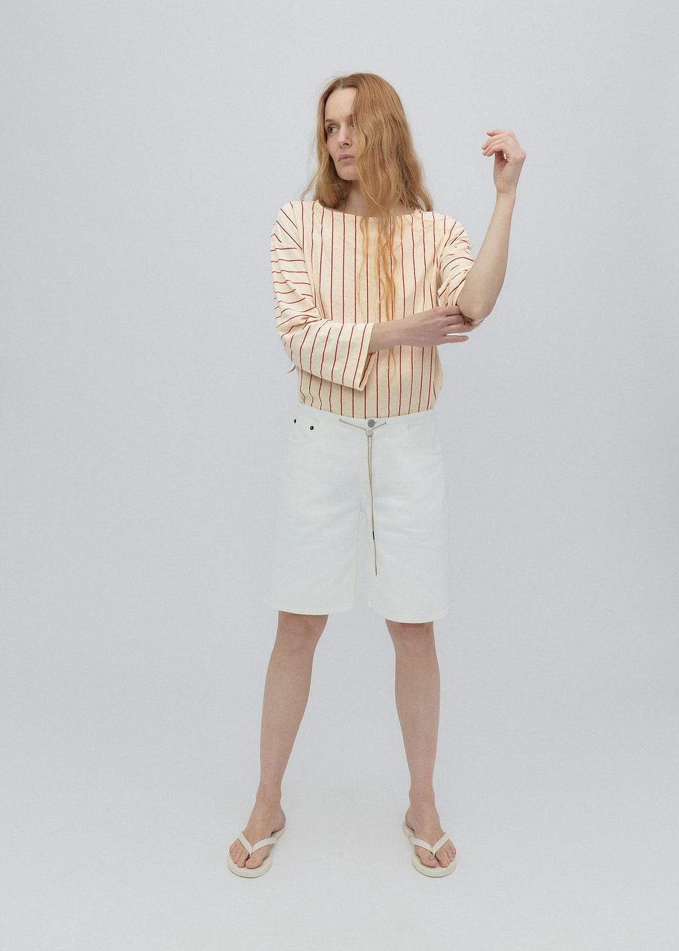 Woman wearing a striped shirt and white skirt on a plain background