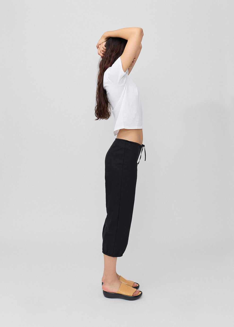 Person wearing a white top and black pants on a light gray background