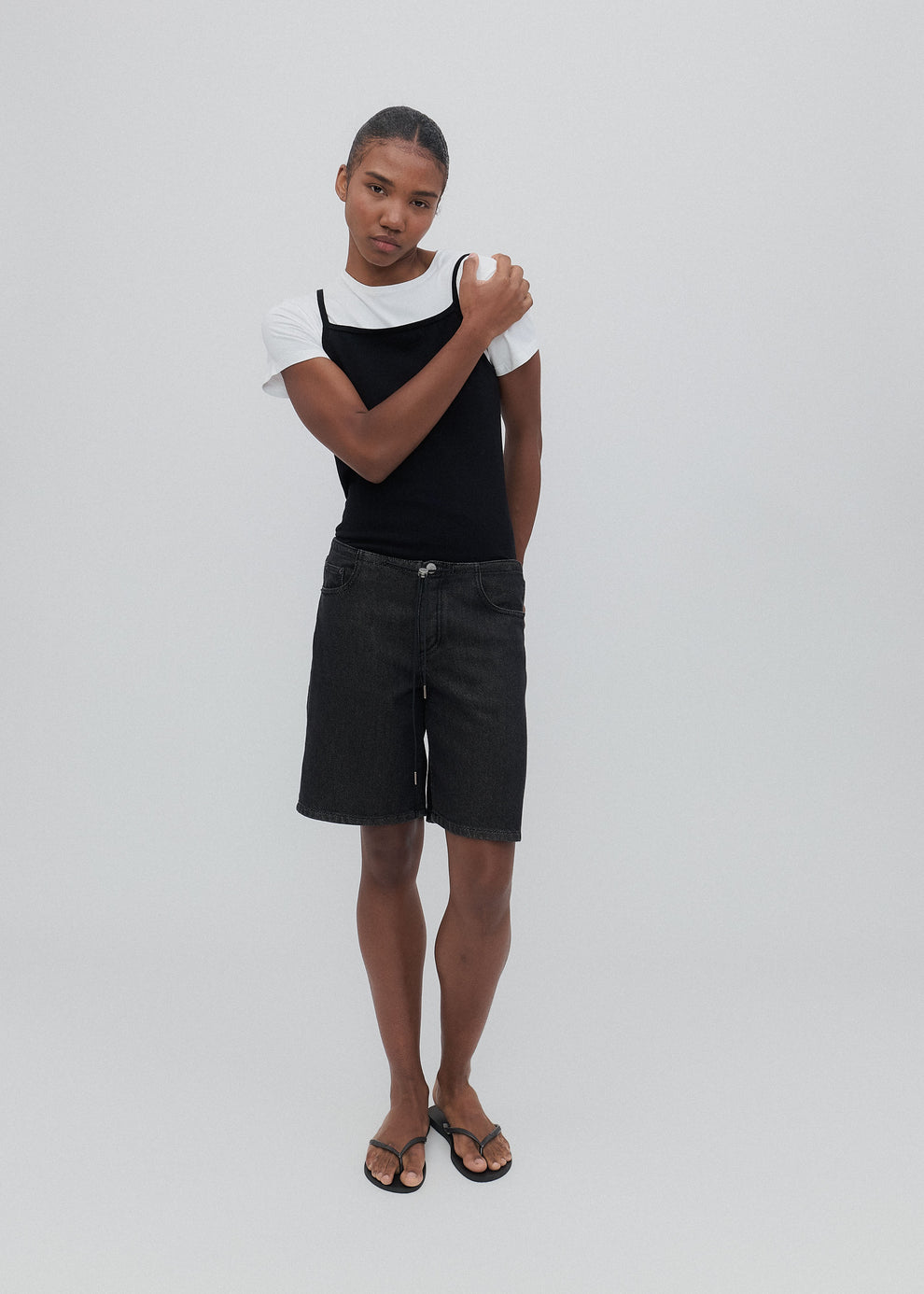 Person wearing a black tank top and shorts on a white background