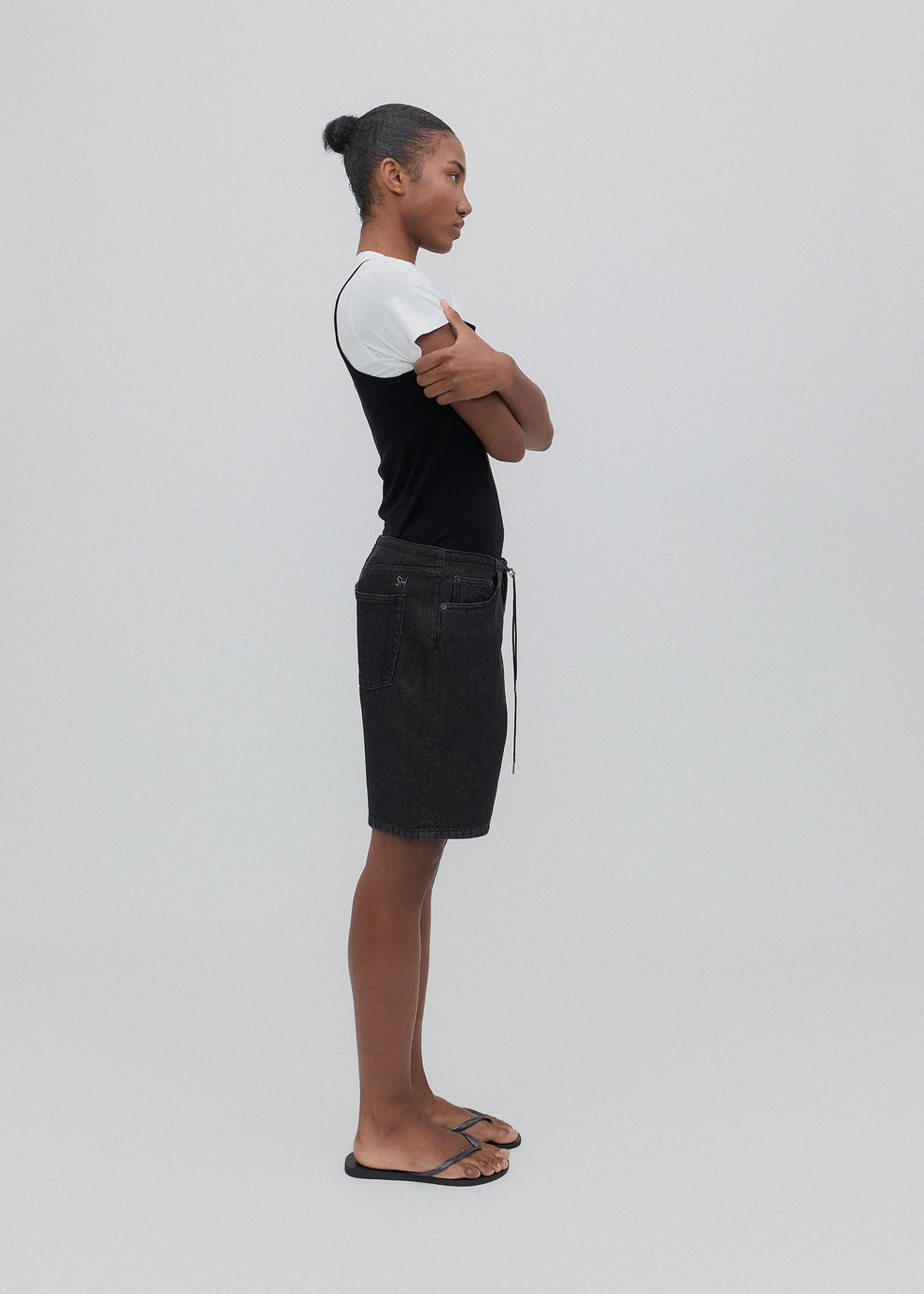 Person wearing a black and white outfit with a denim skirt on a plain background