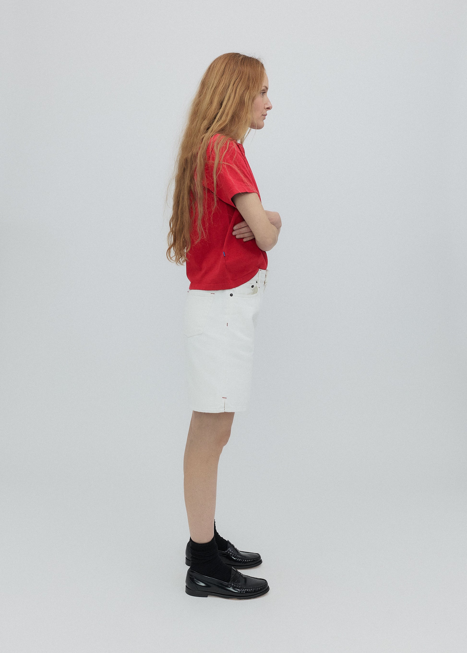 Person wearing a red shirt and white shorts standing against a plain background