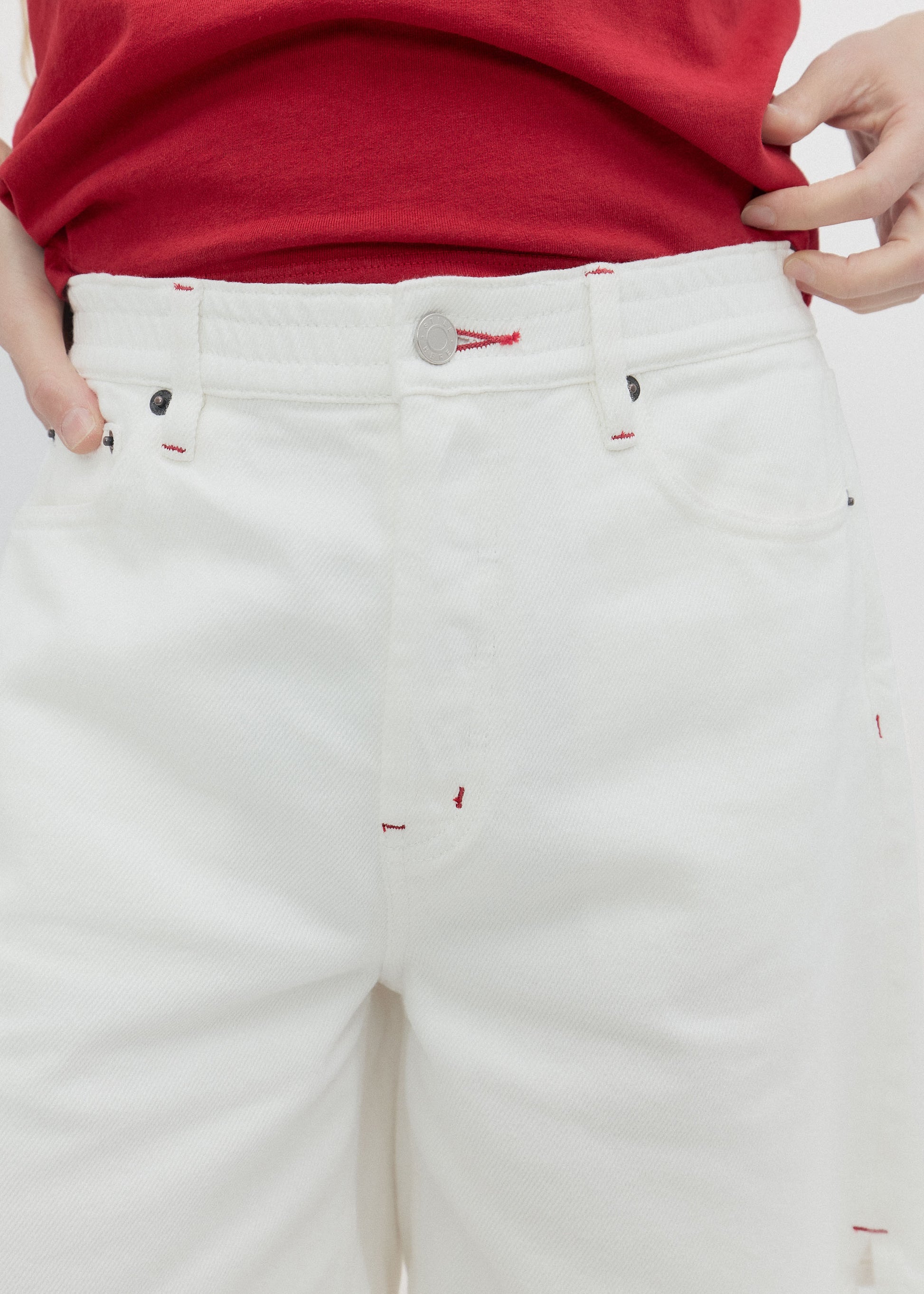 White pants with red accents worn by a person, focusing on the waist area.