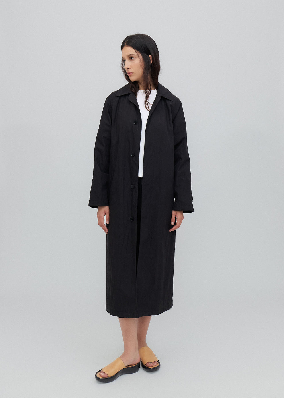 Person wearing a black coat on a light gray background