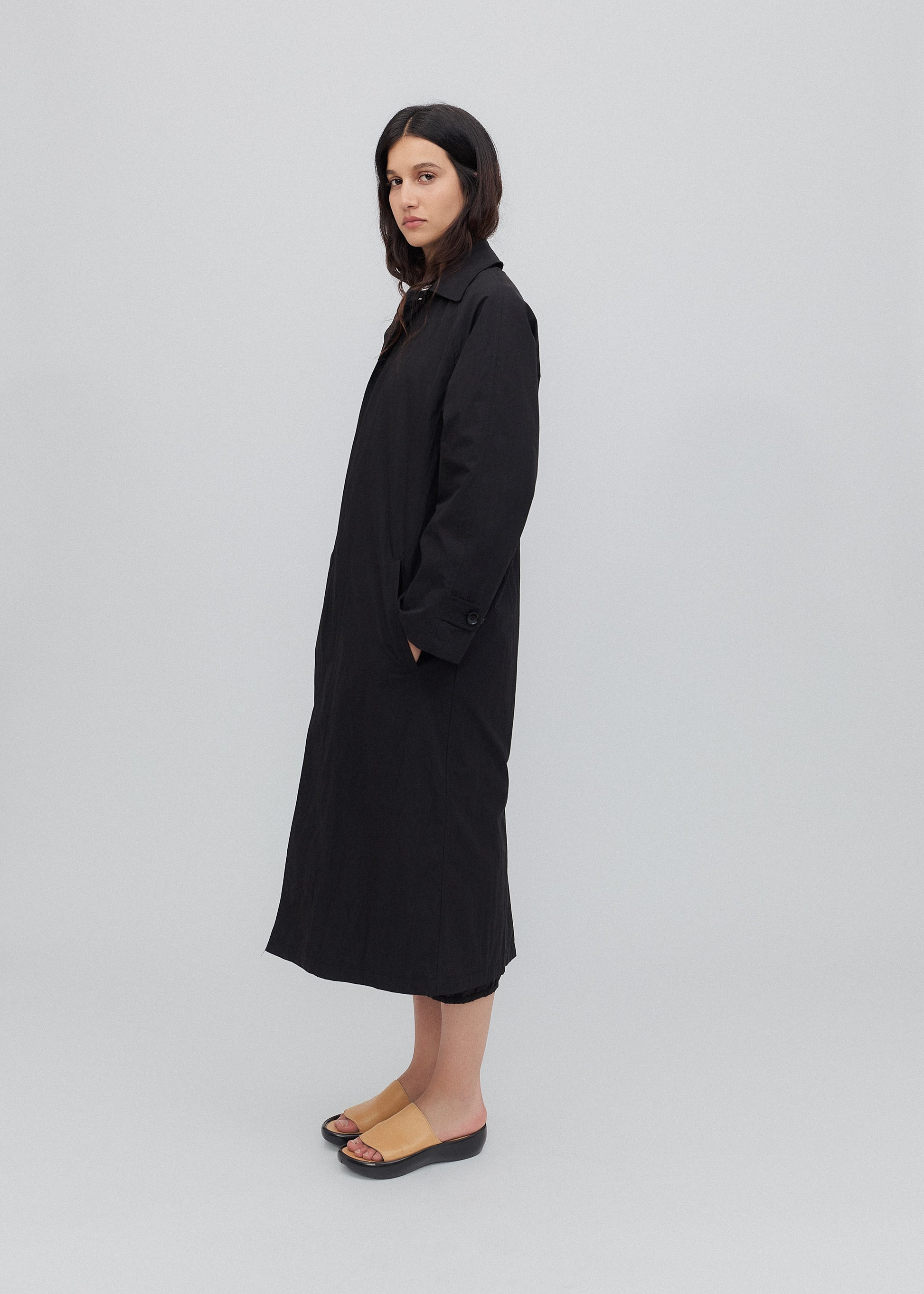 Woman wearing a black coat on a light gray background