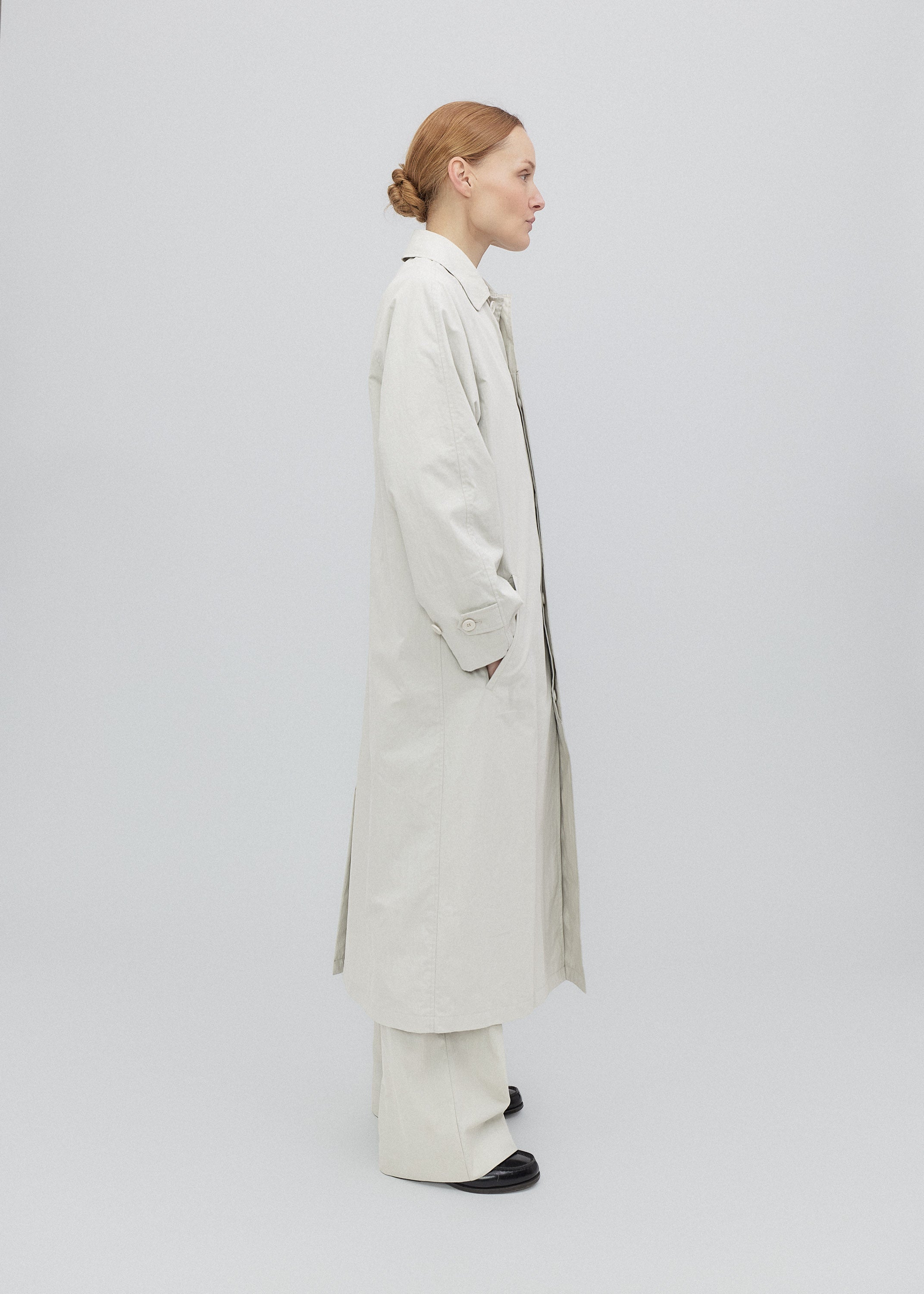 Woman wearing a long beige coat on a white background