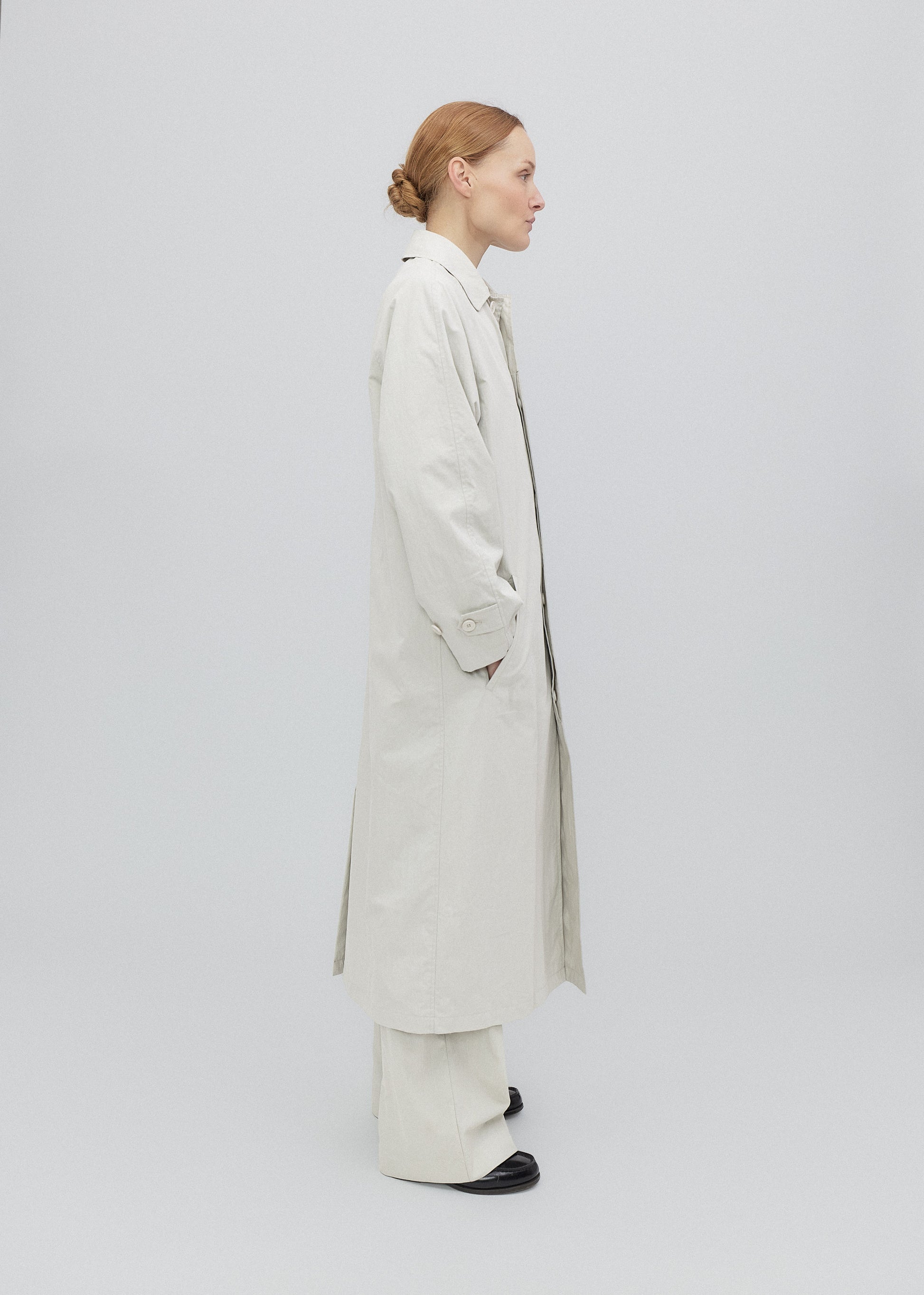Woman wearing a long beige coat on a white background