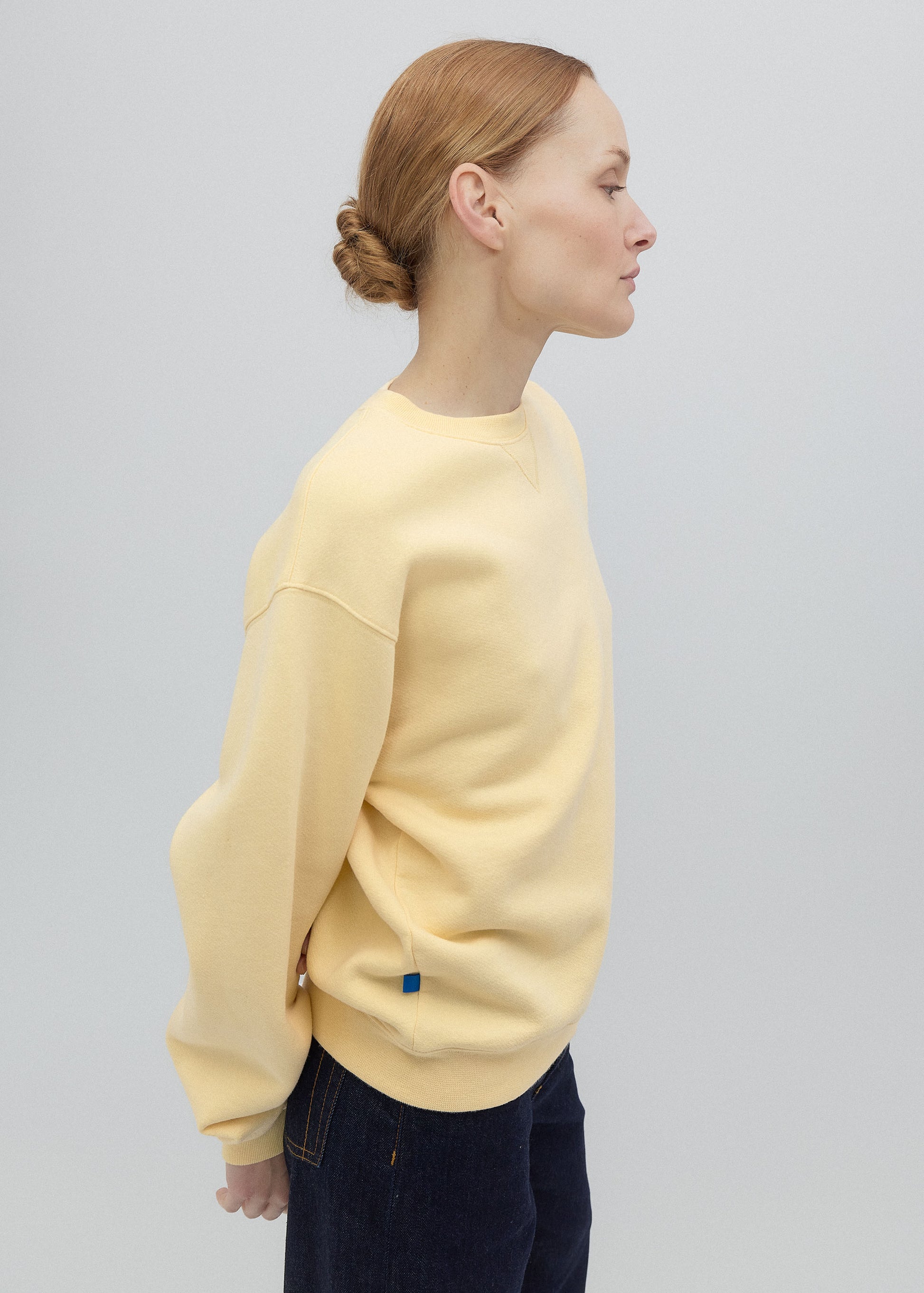 Person wearing a light yellow sweater on a plain background