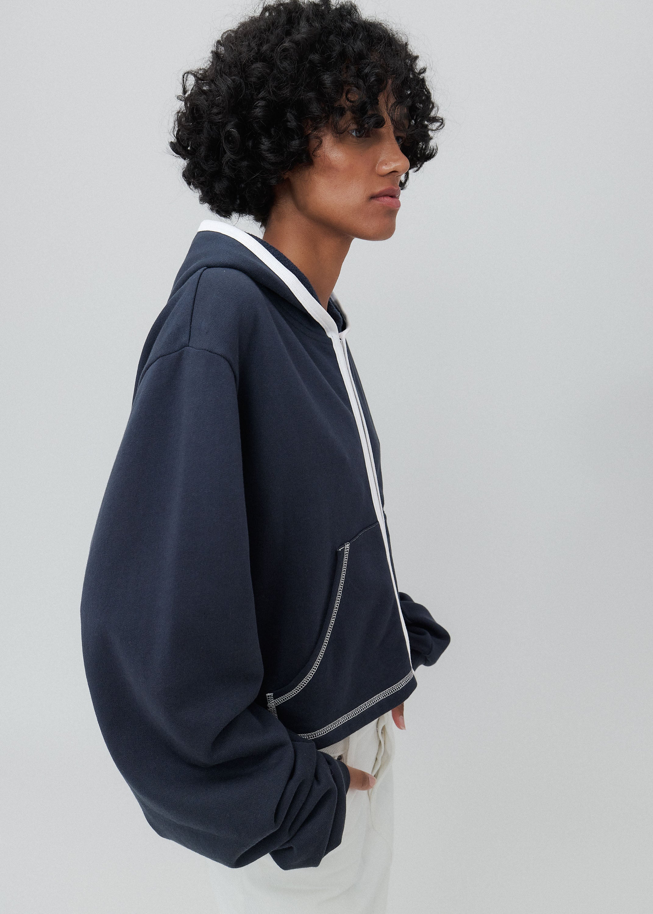 Person wearing a dark blue hoodie with white accents on a light gray background