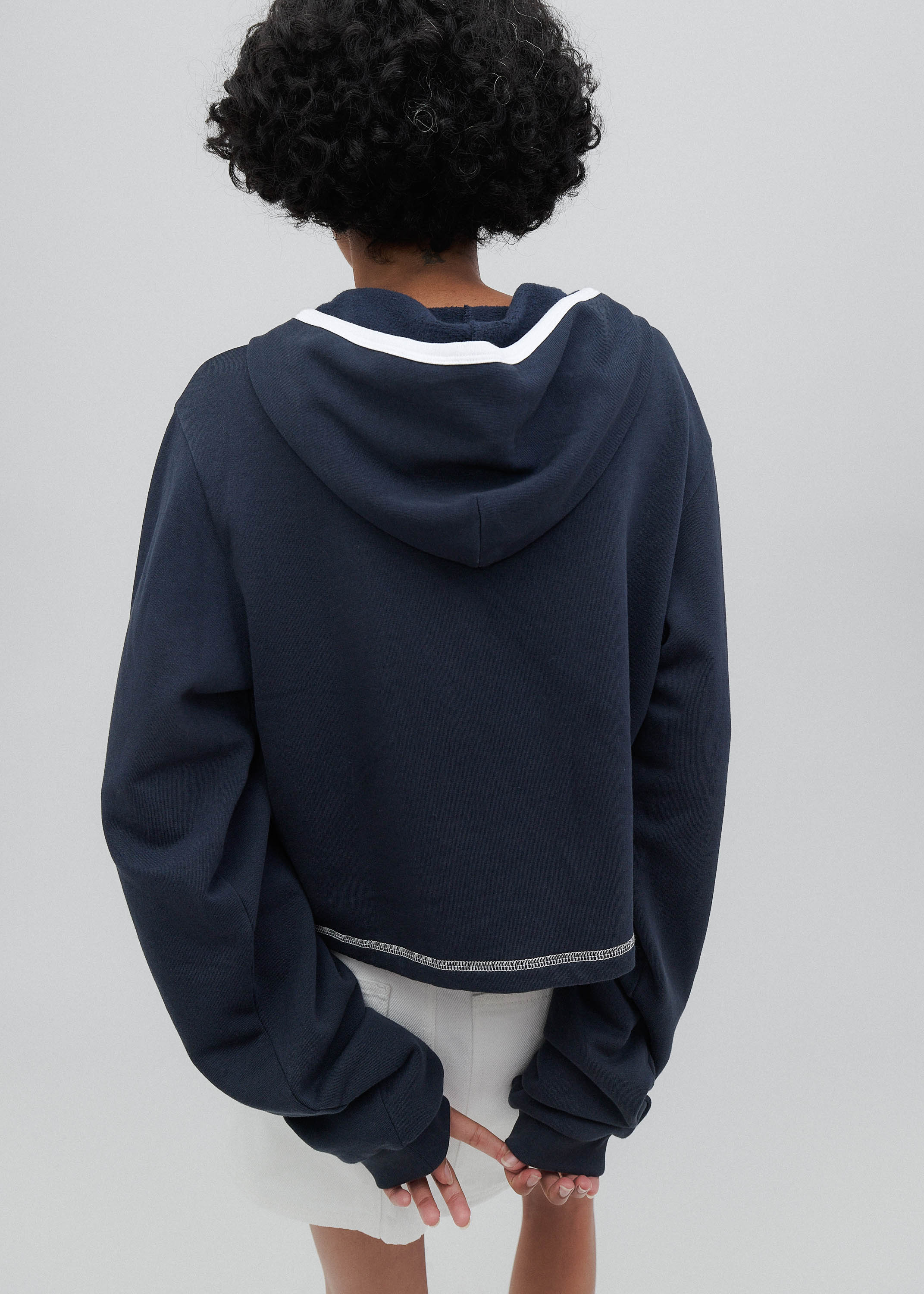 Person wearing a navy blue hoodie with white trim on a plain background