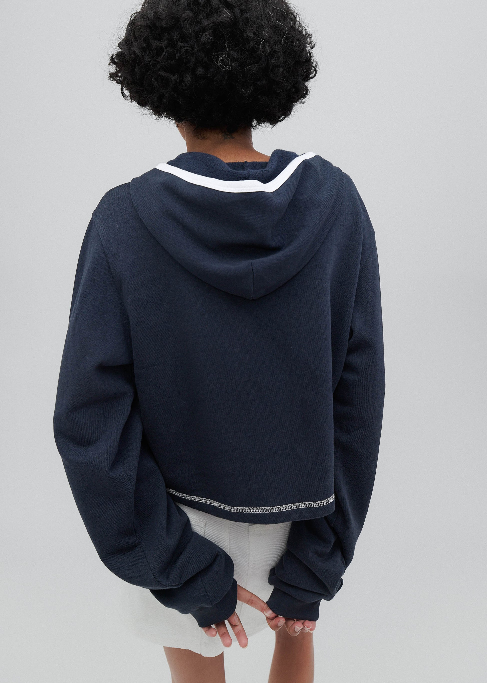 Person wearing a navy blue hoodie with white trim on a plain background