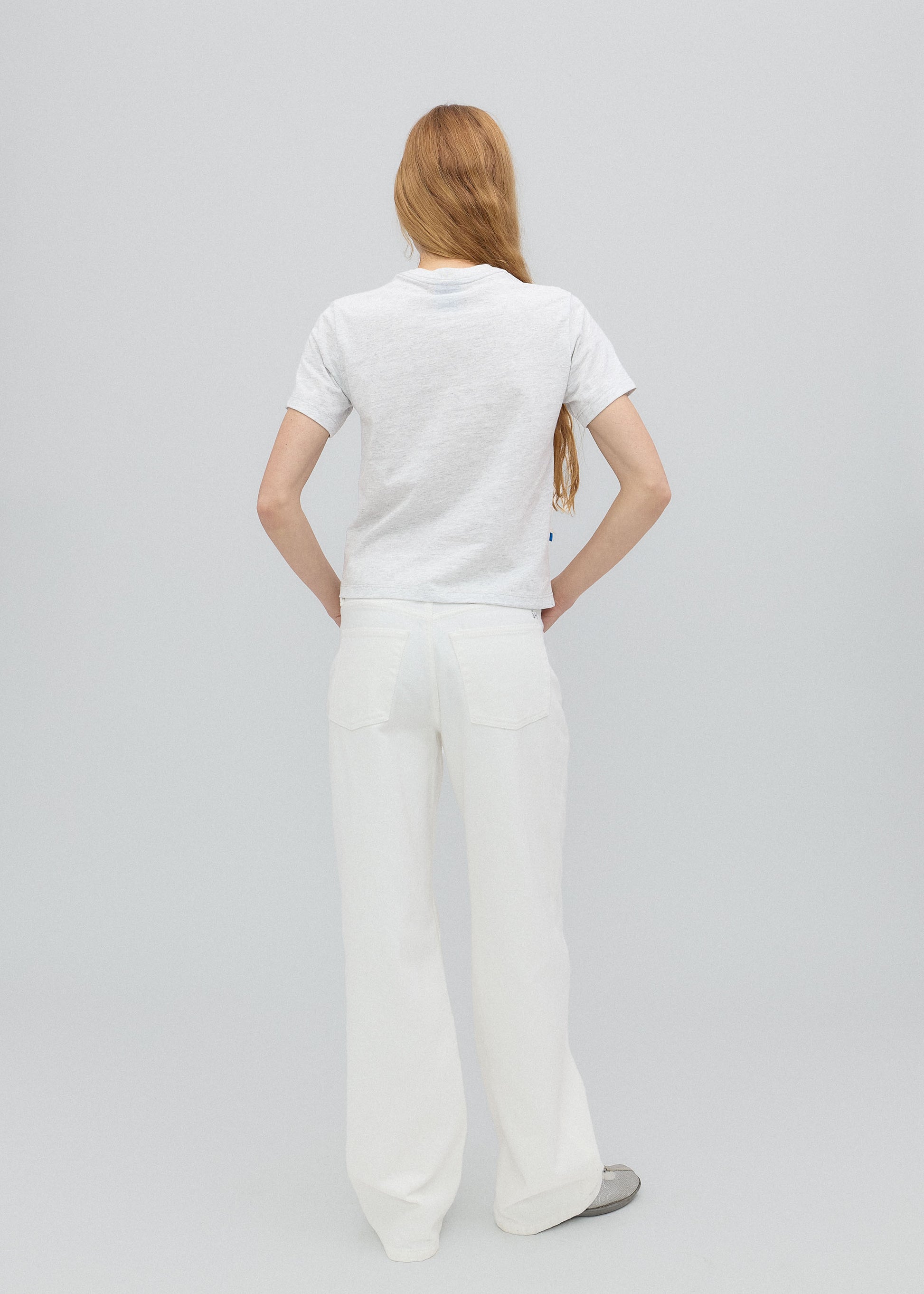 Person wearing a white t-shirt and pants on a light gray background
