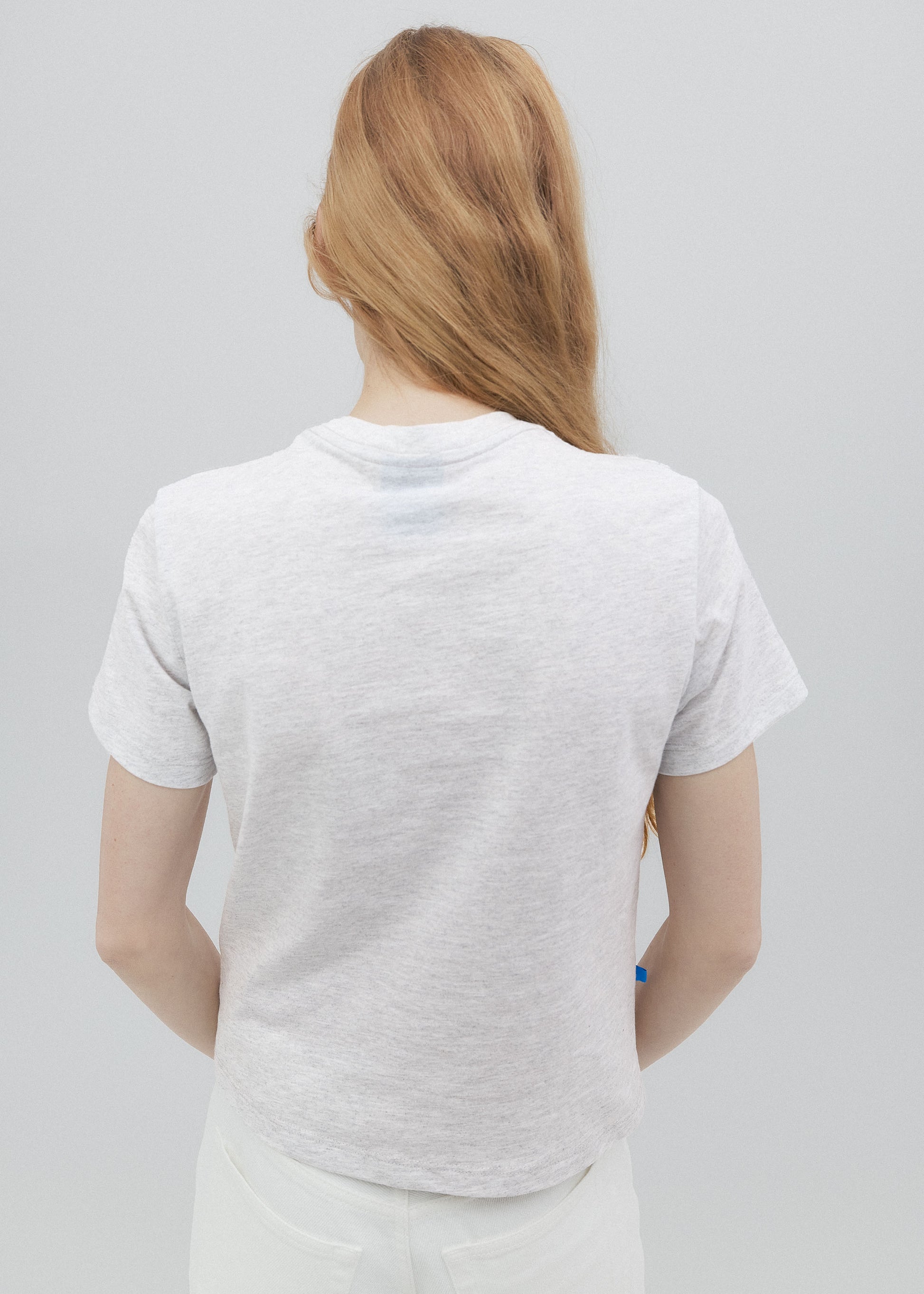 Person wearing a plain white t-shirt against a light gray background