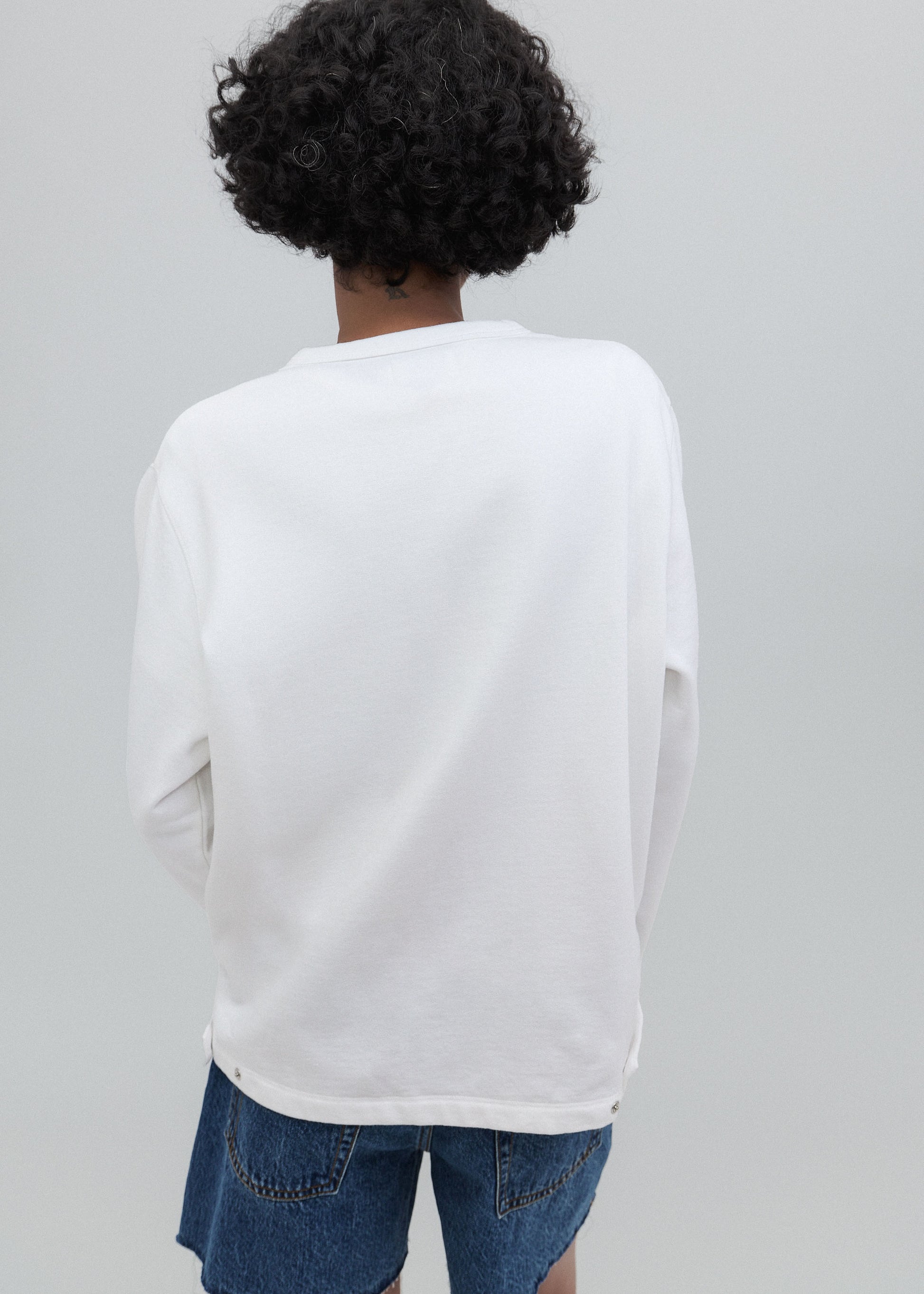 Person wearing a white long-sleeve shirt and blue jeans on a gray background