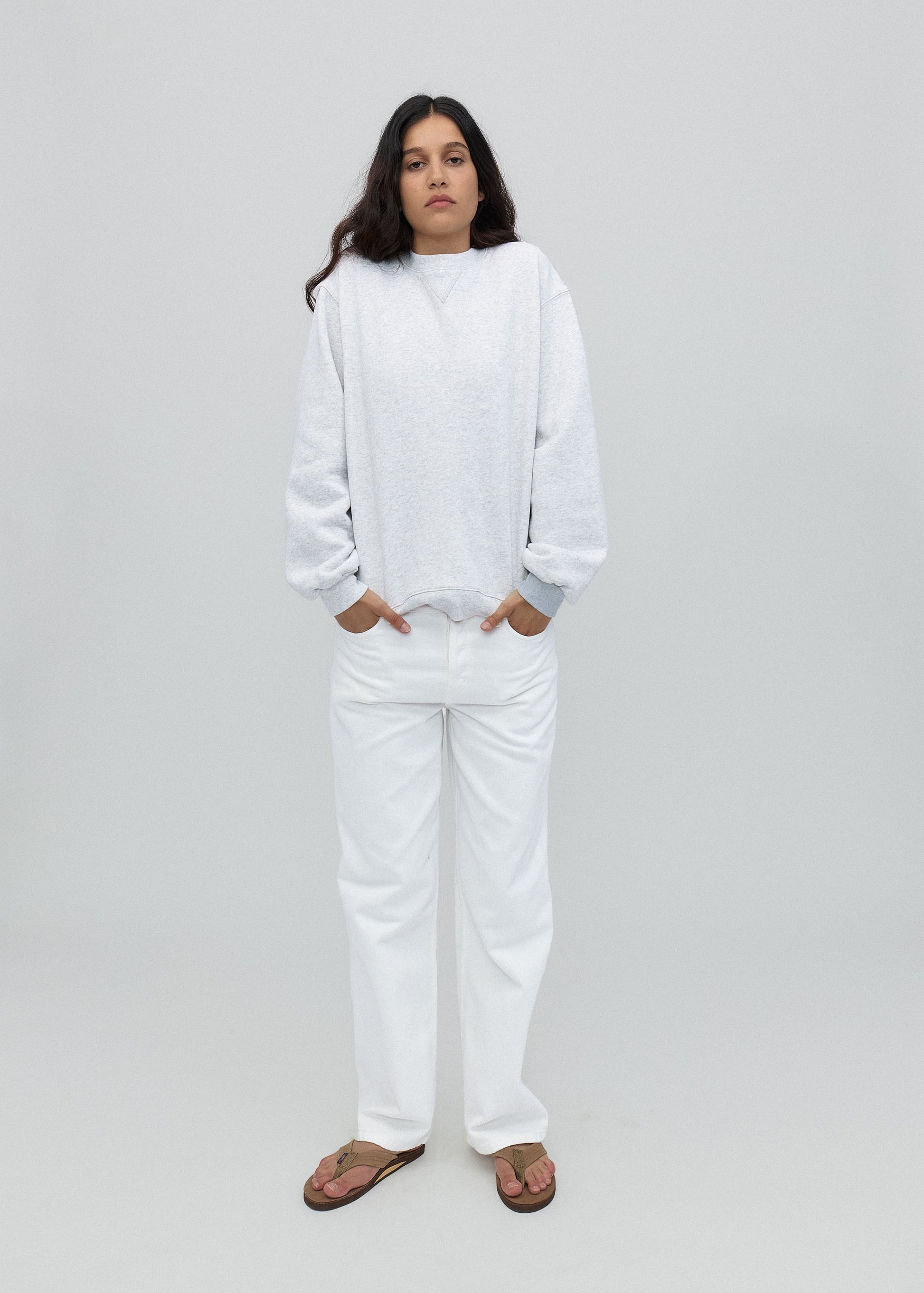Person wearing a white sweatshirt and pants on a light gray background
