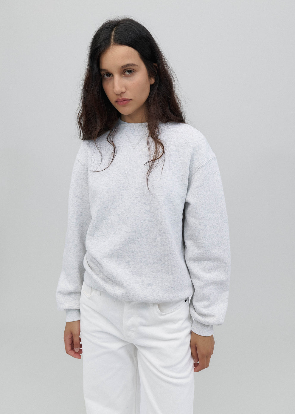Woman wearing a light gray sweatshirt and pants on a plain background