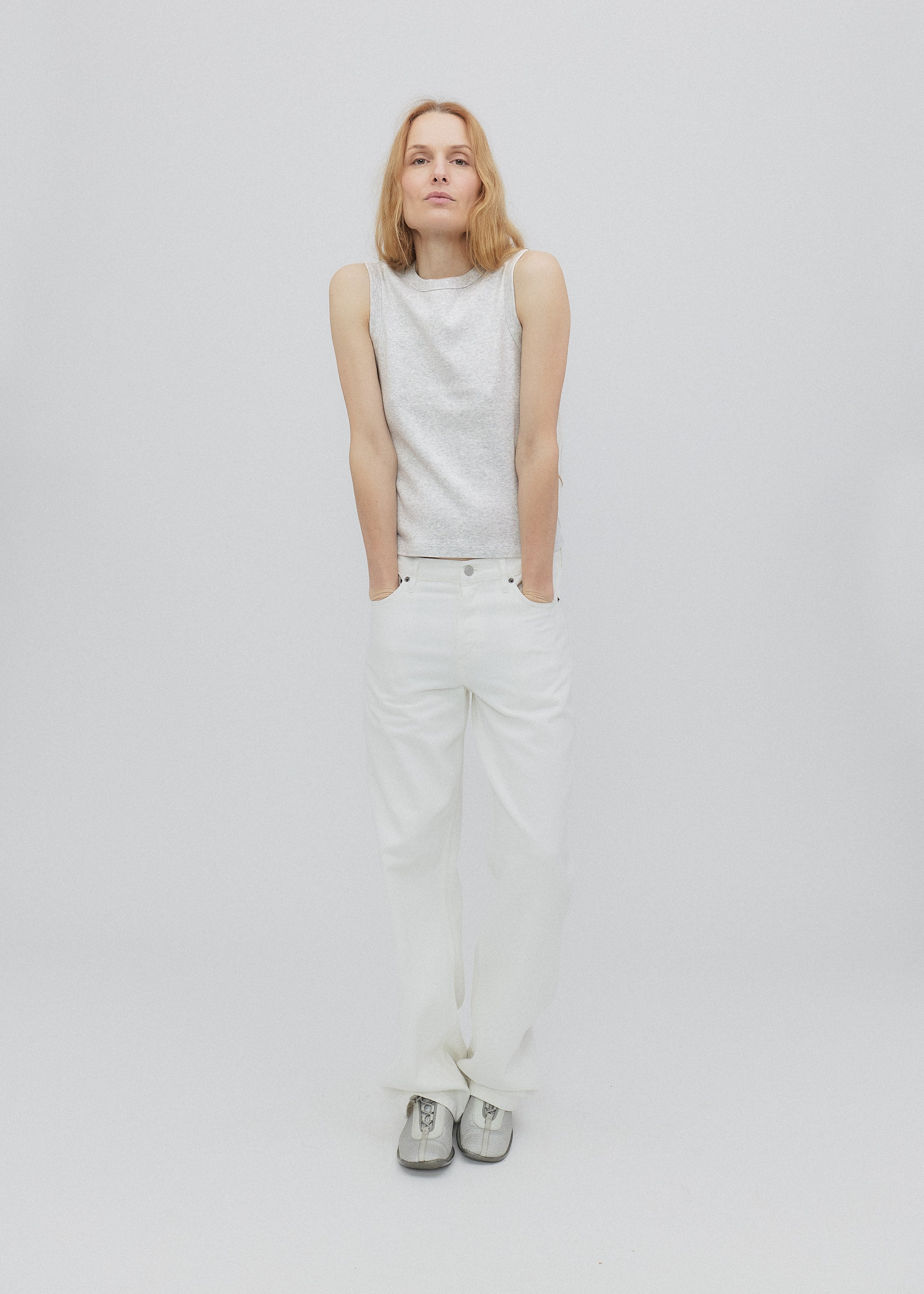 Person wearing a white sleeveless top and pants on a light gray background
