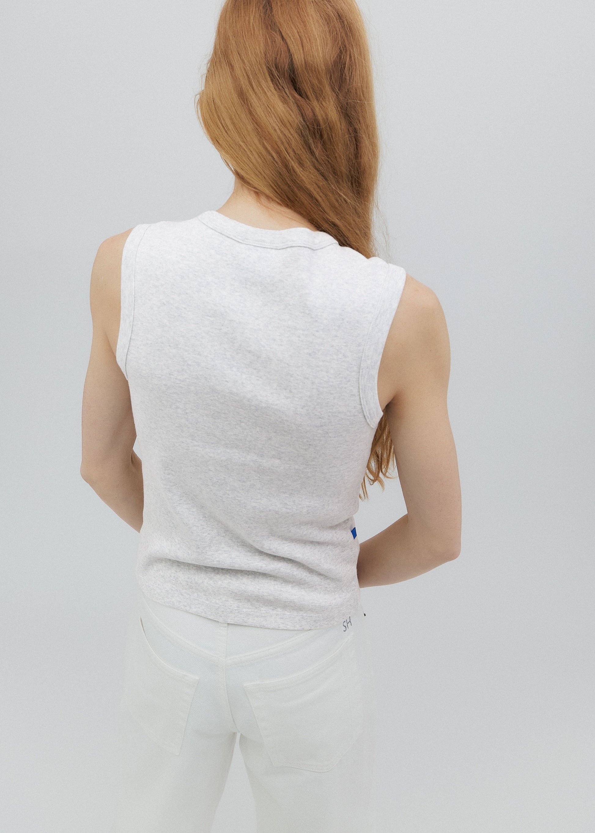 Person wearing a white sleeveless top and pants on a plain background