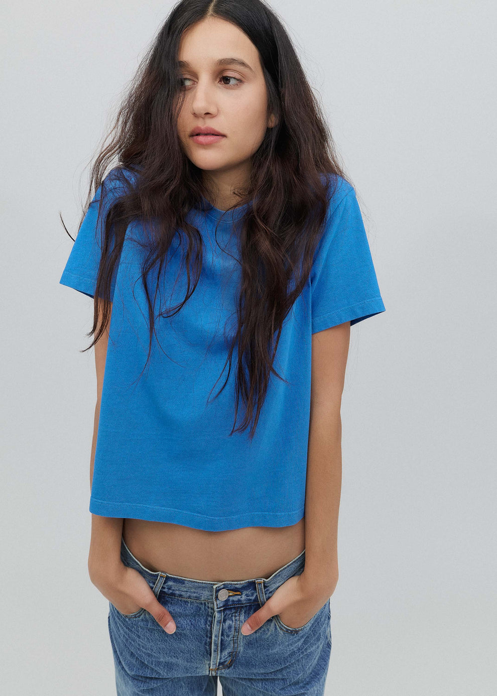 Person wearing a blue t-shirt and jeans against a plain background