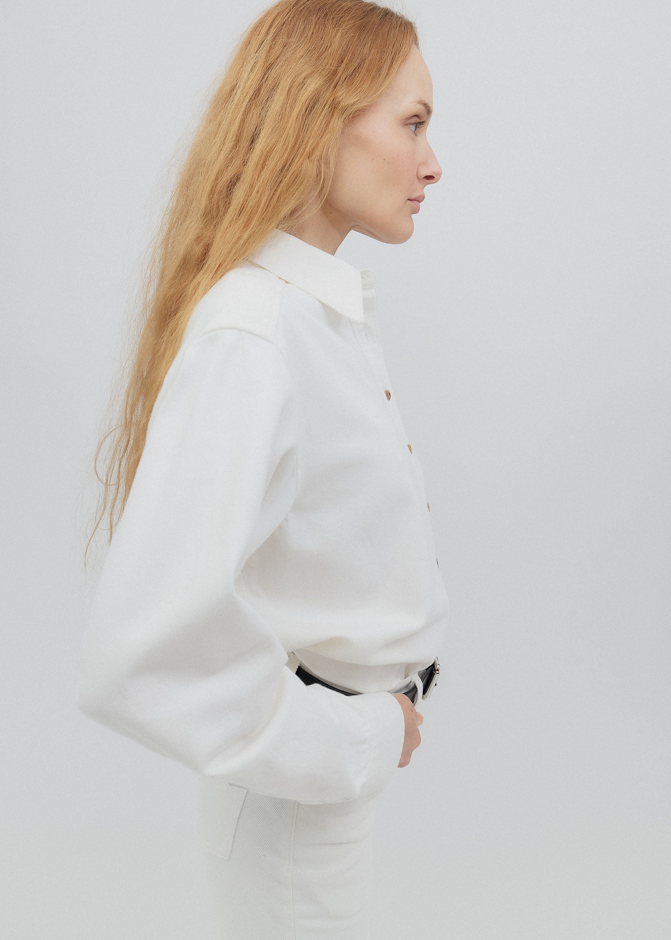 Woman wearing a white outfit with a visible brand logo on a light gray background
