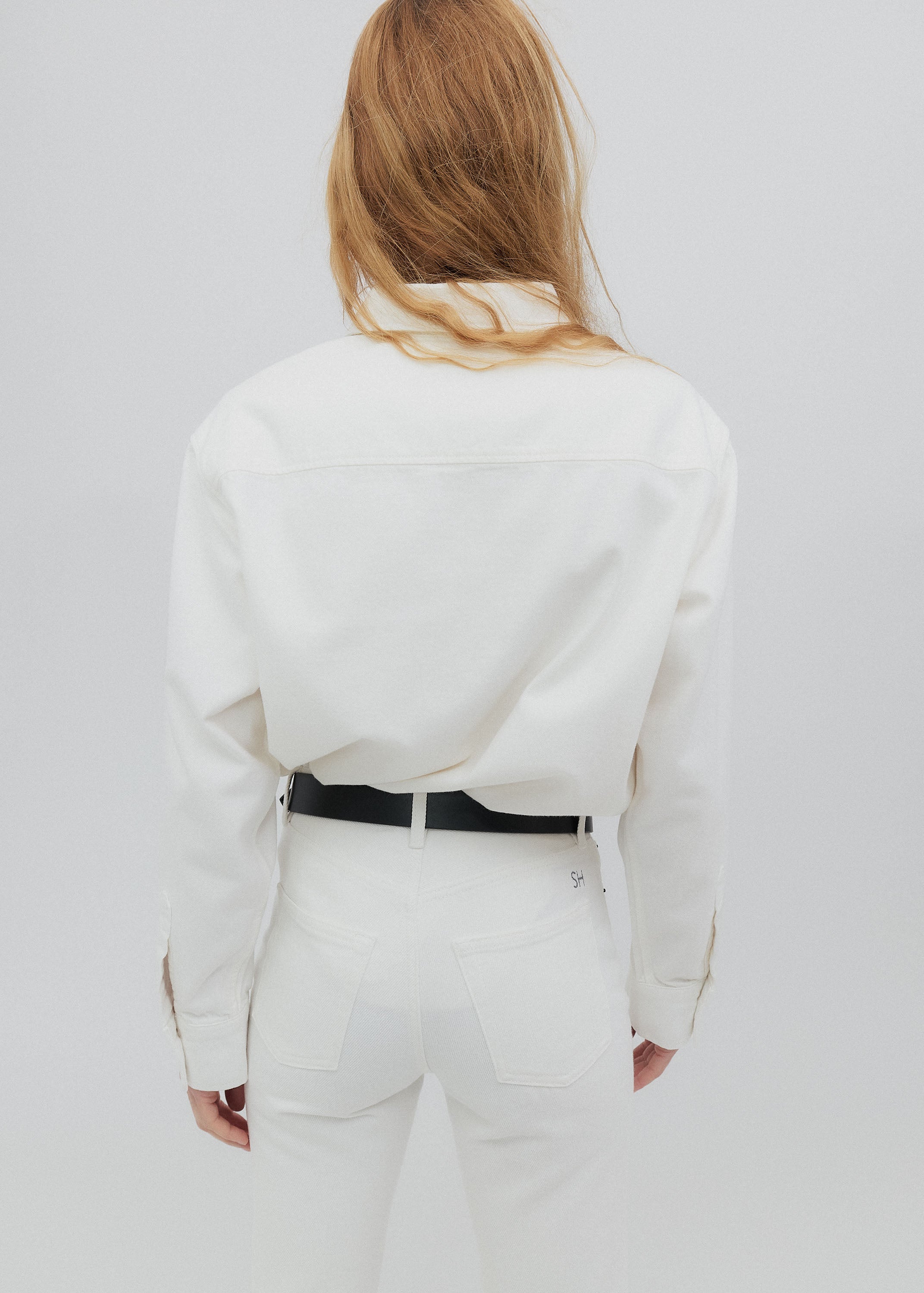 Person wearing a white outfit with a black belt on a plain background