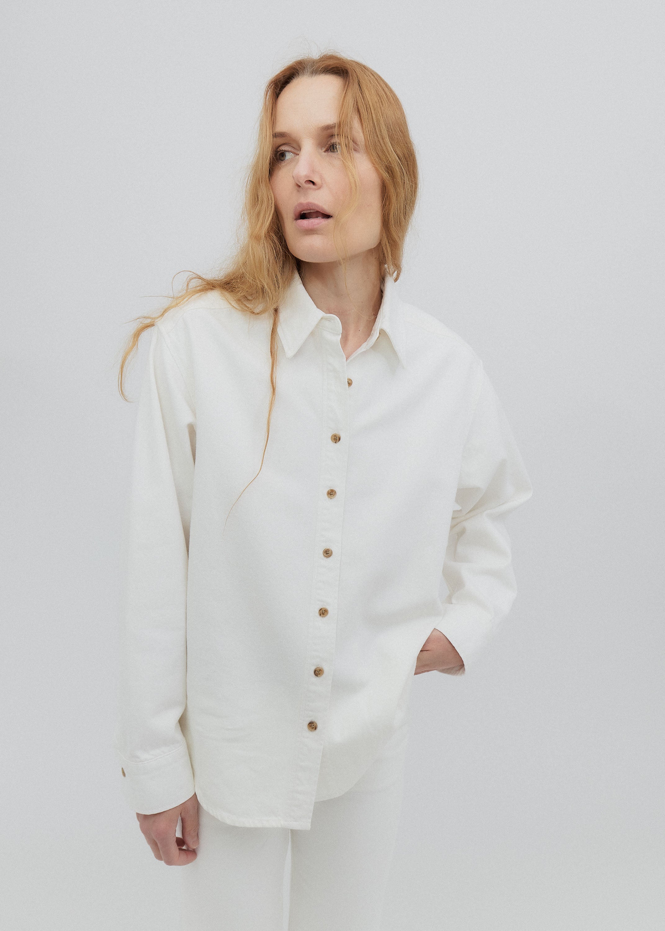 Woman wearing a white button-up shirt against a plain background