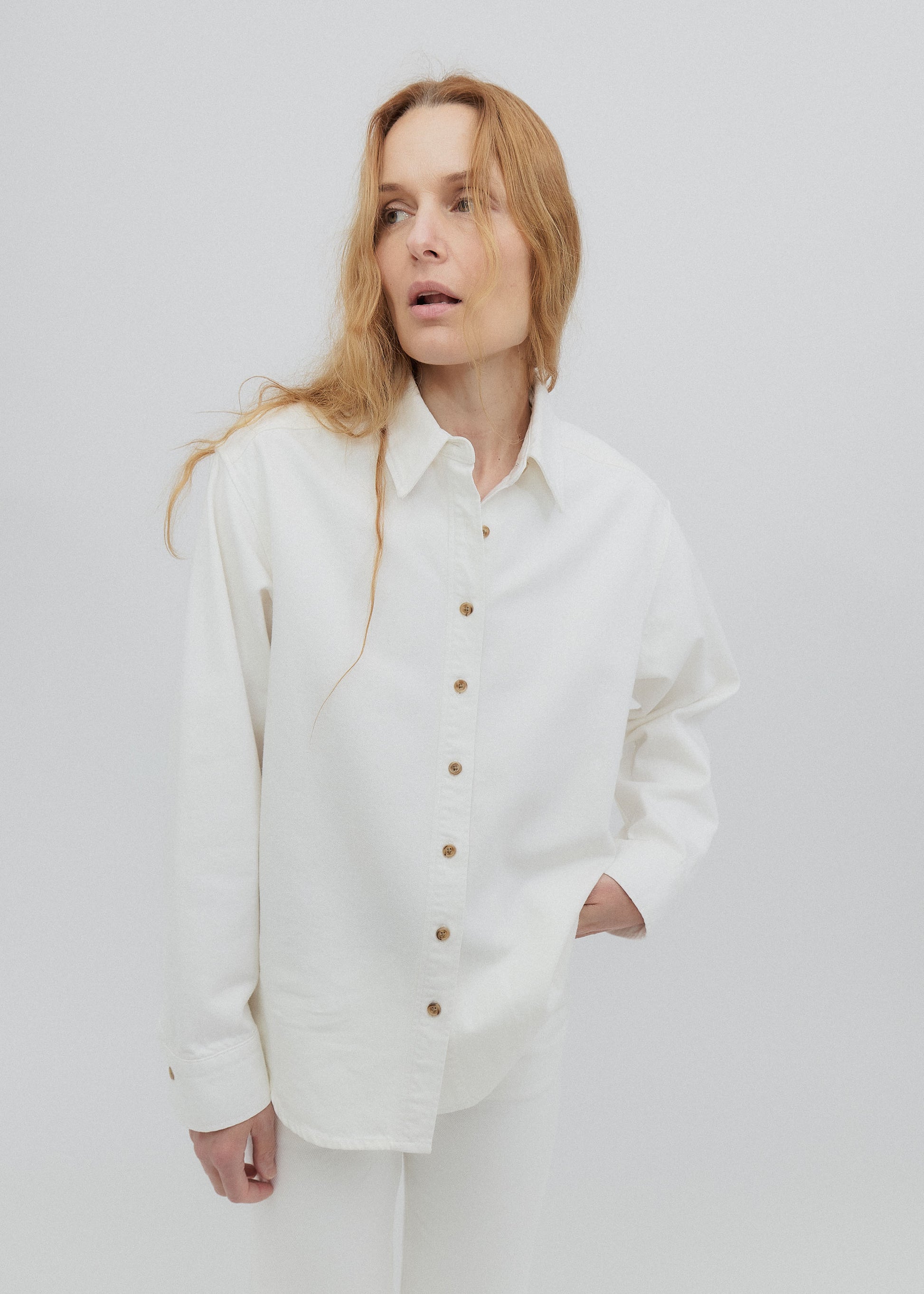 Woman wearing a white button-up shirt against a plain background