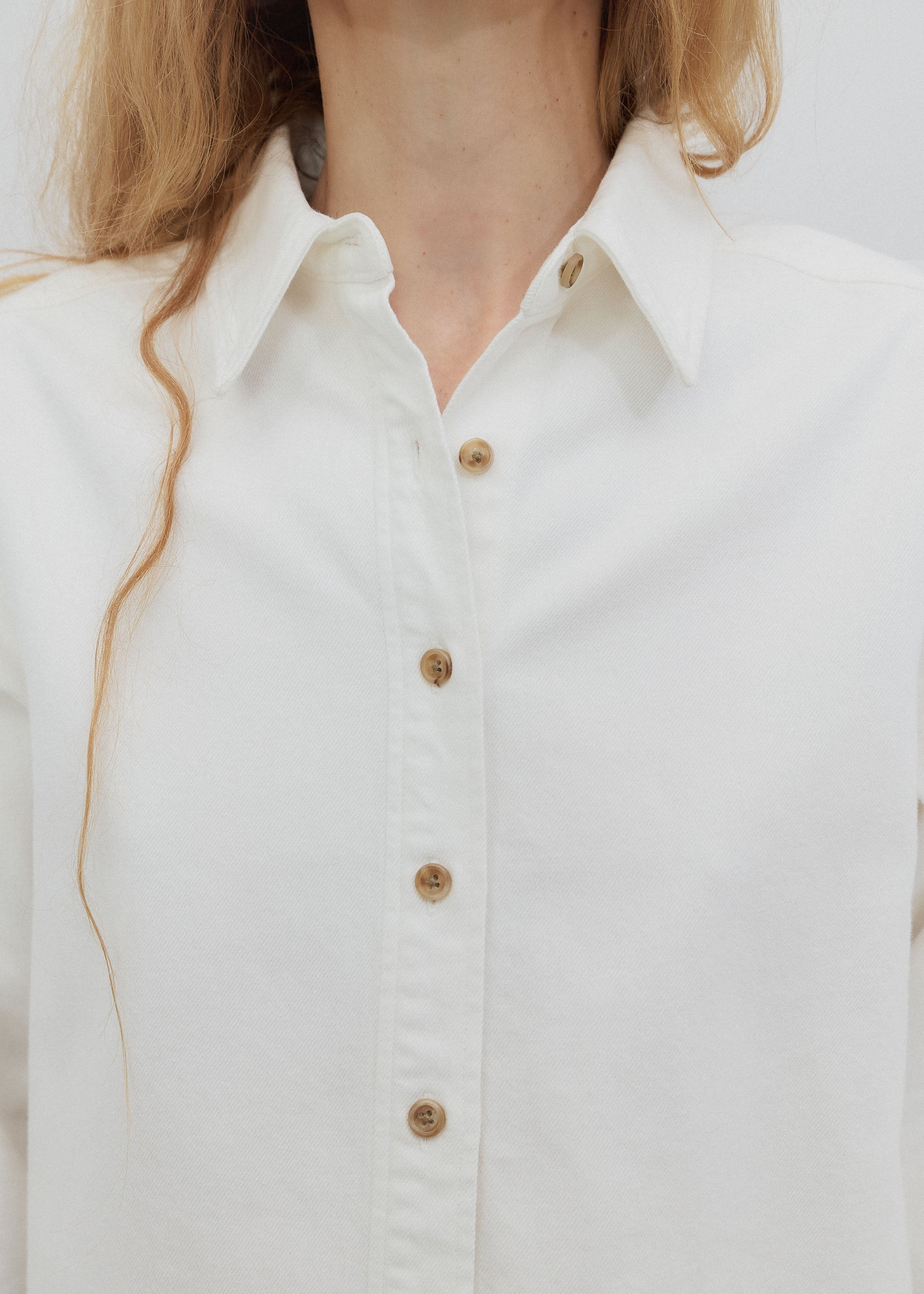 Close-up of a white shirt with gold buttons on a plain background