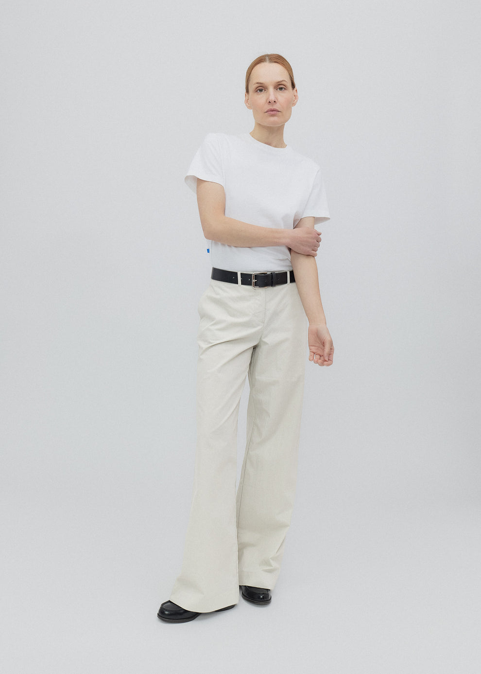 Person wearing a white t-shirt and beige pants on a plain background