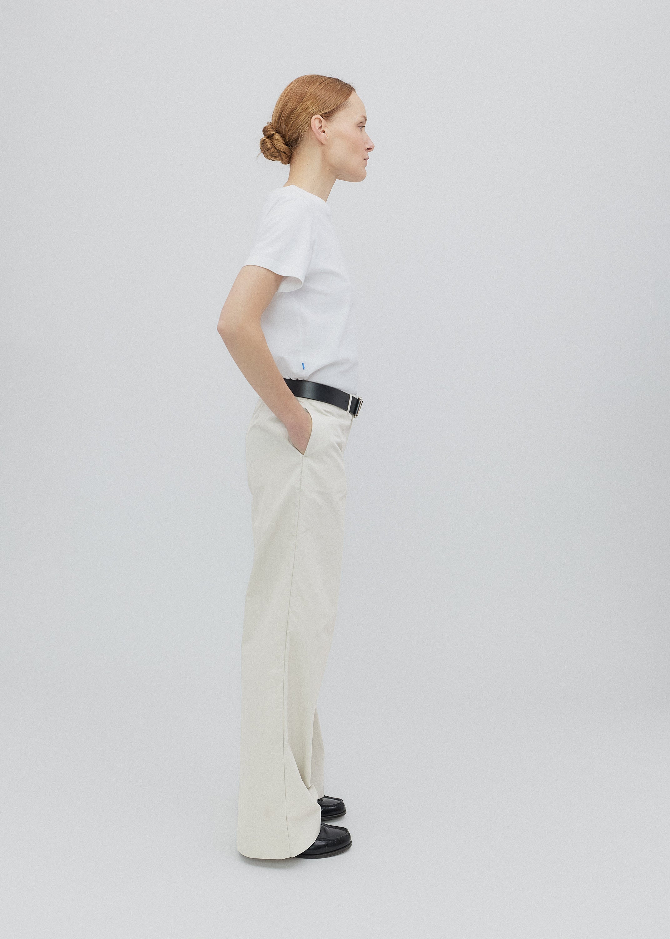 Person wearing a white shirt and beige pants on a plain background