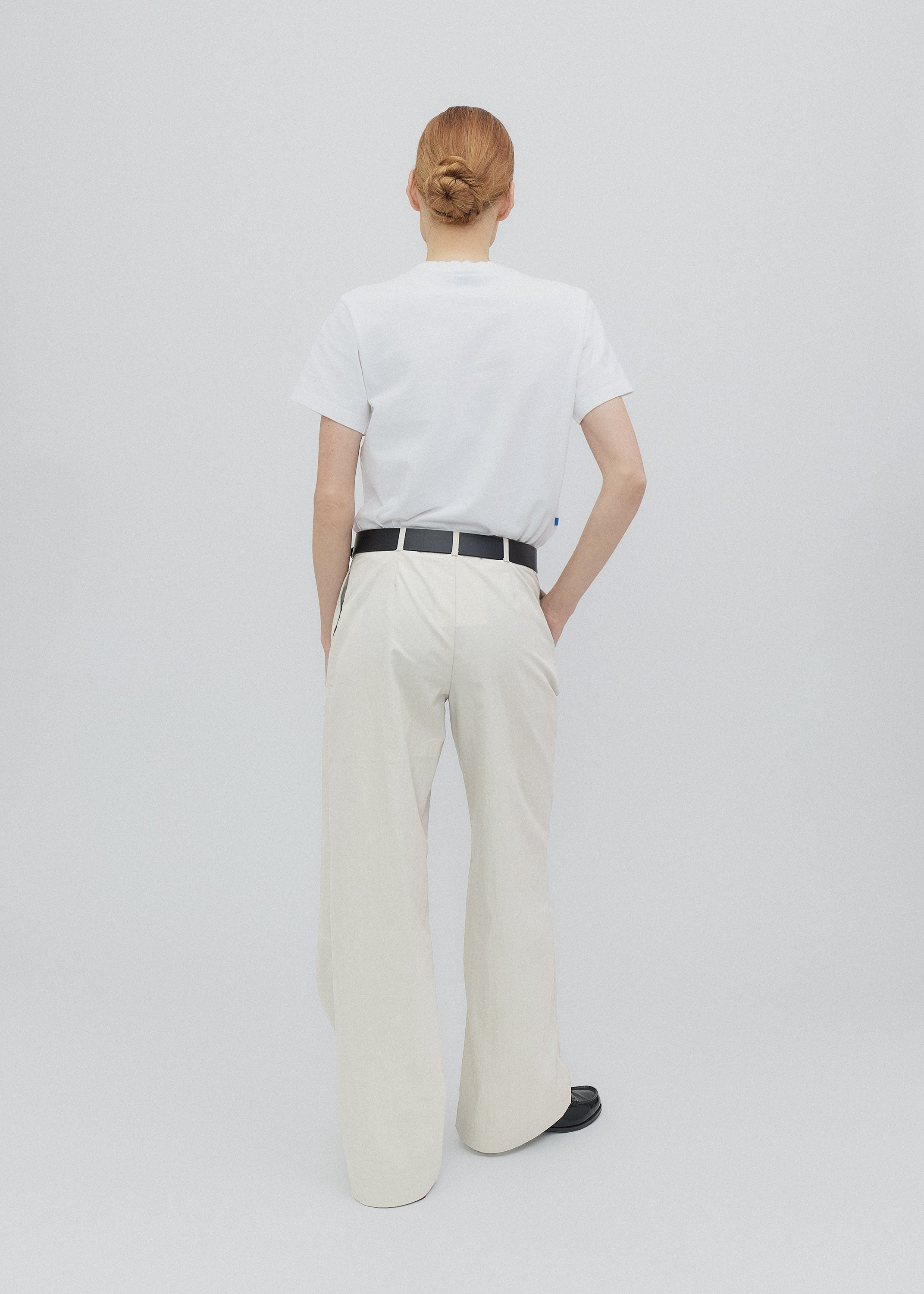 Person wearing a white t-shirt and beige pants on a plain background