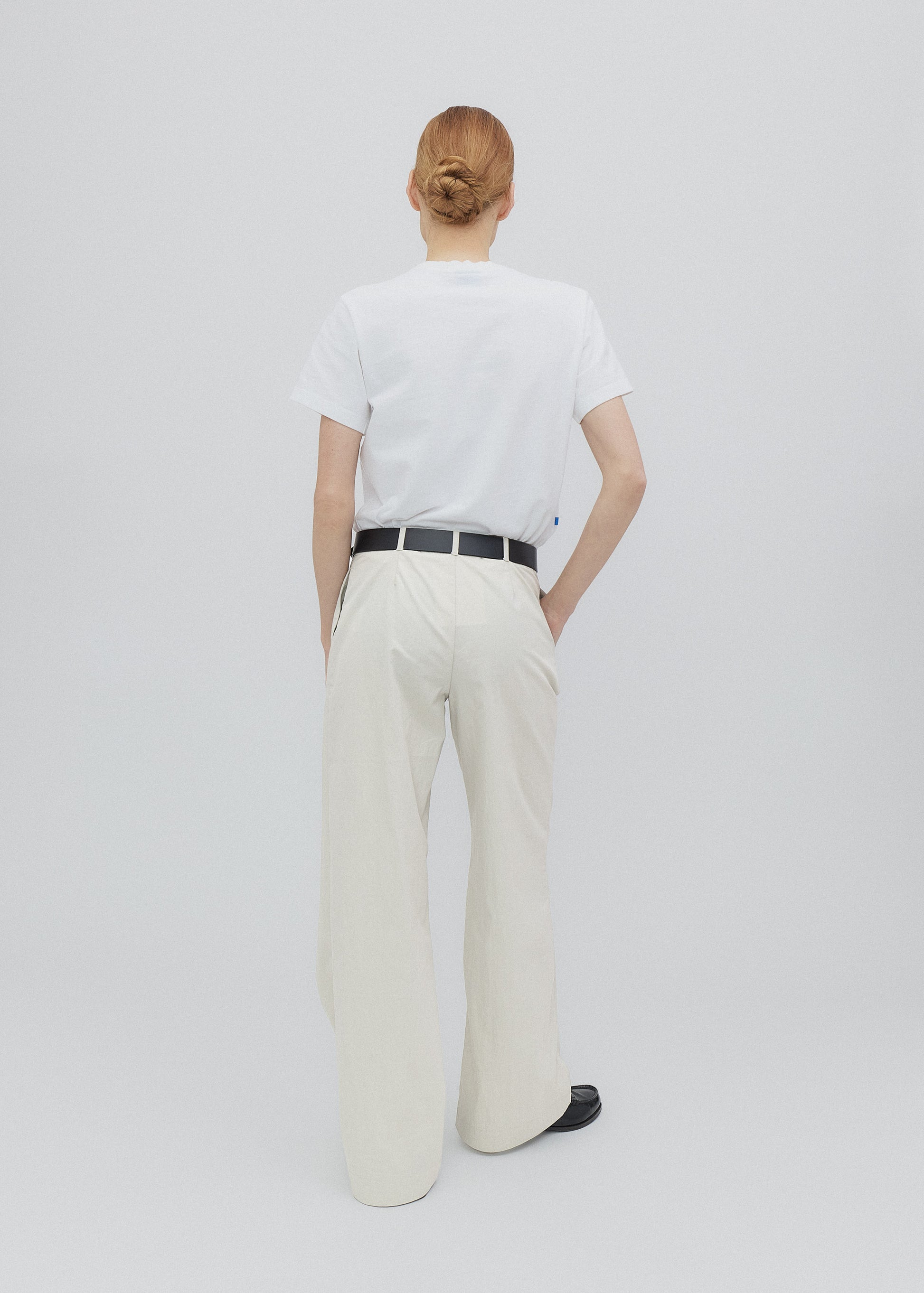 Person wearing a white t-shirt and beige pants on a plain background