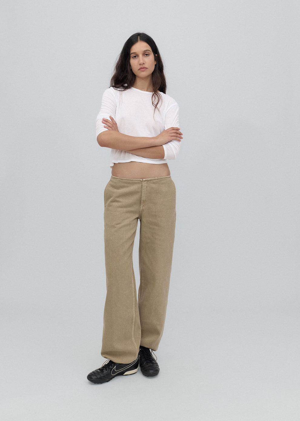 Woman wearing a white top and beige pants on a light gray background