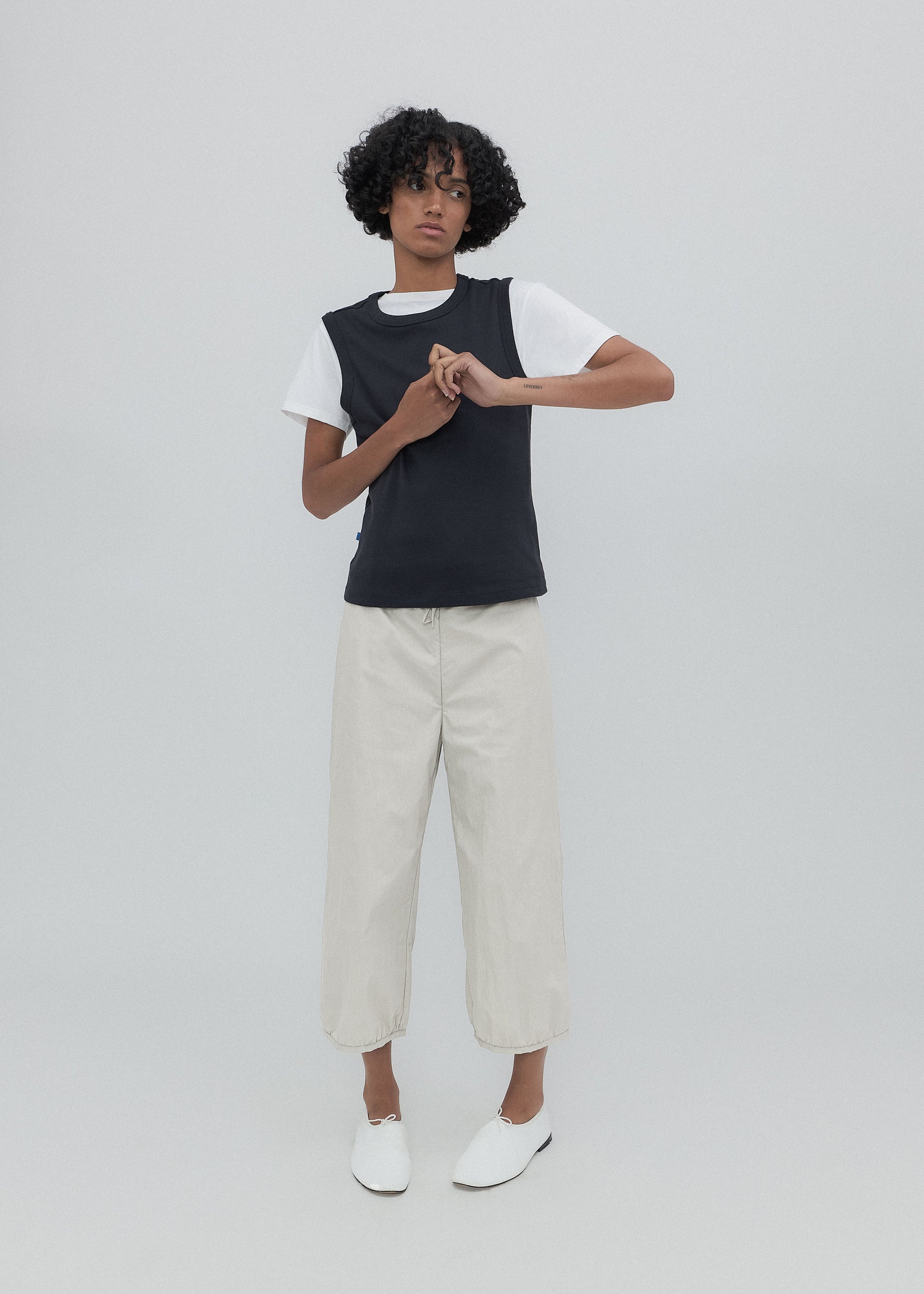 Person wearing a black and white top with beige pants on a plain background