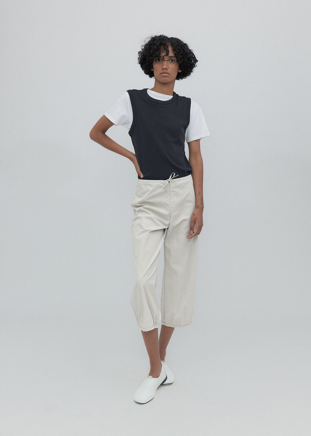 Person wearing a black and white t-shirt with beige pants on a plain background