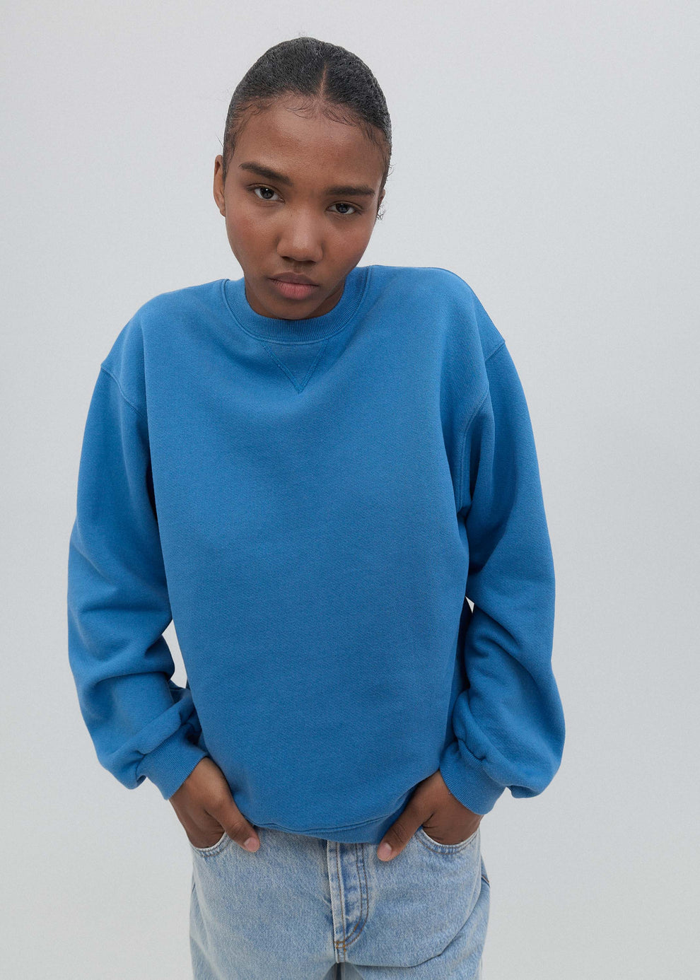 Person wearing a blue sweatshirt against a plain background