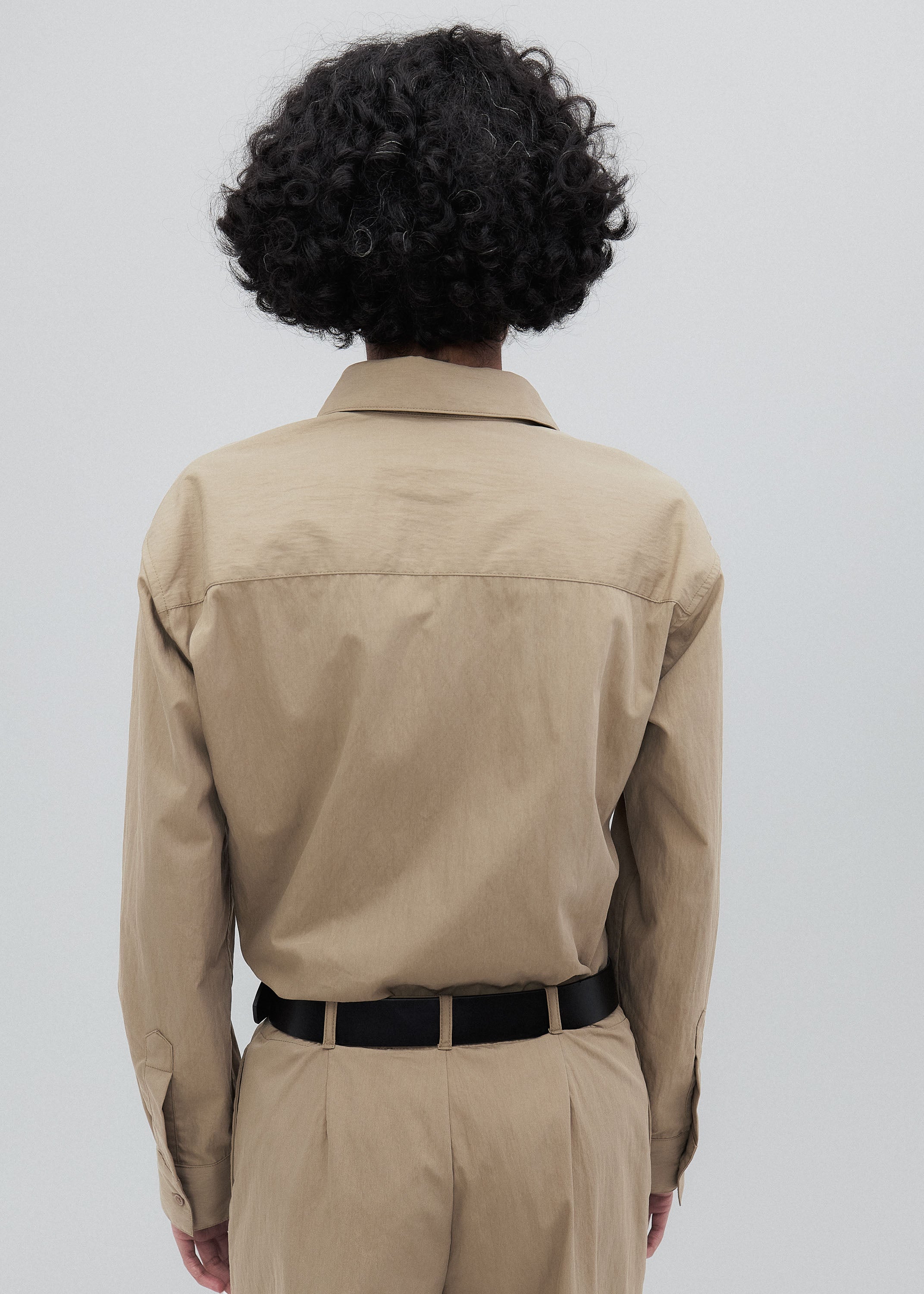 Person wearing a beige jacket and pants on a plain background