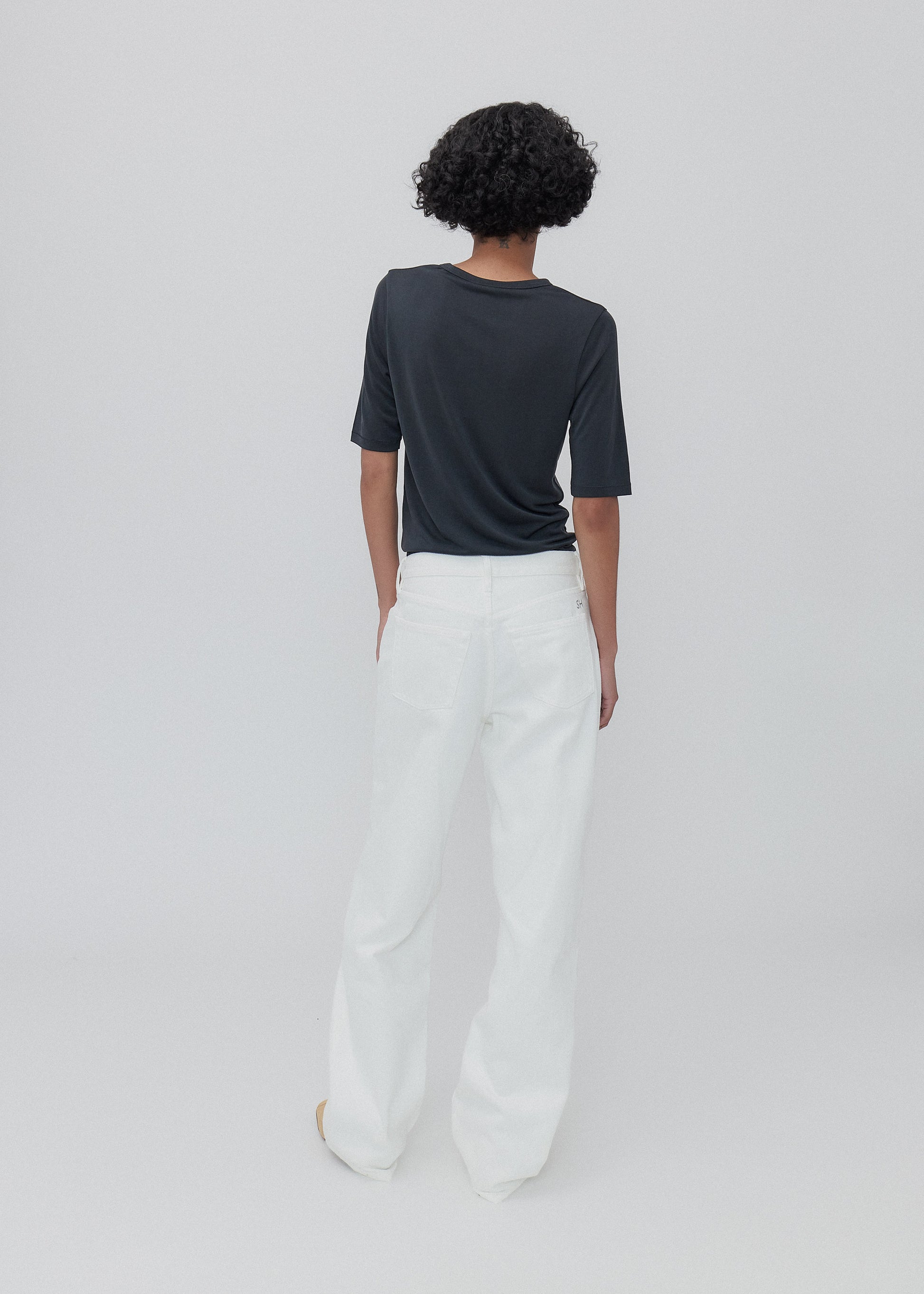 Person wearing a black top and white pants on a plain background