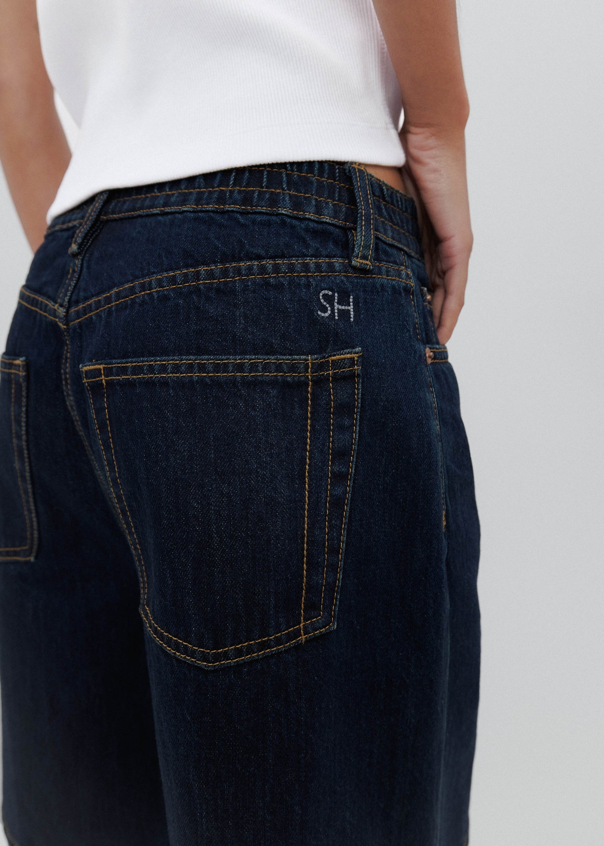 Dark blue jeans with a brand logo on the back pocket against a white background