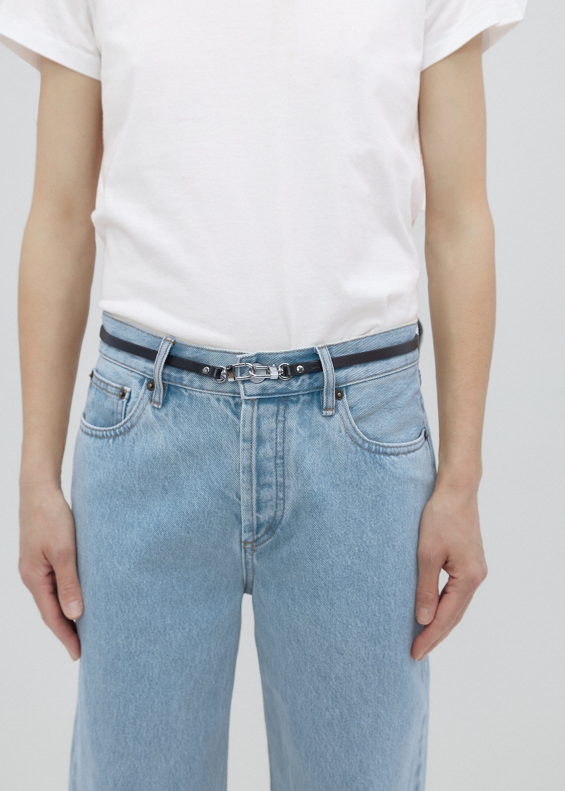 Person wearing light blue jeans and a white t-shirt on a plain background
